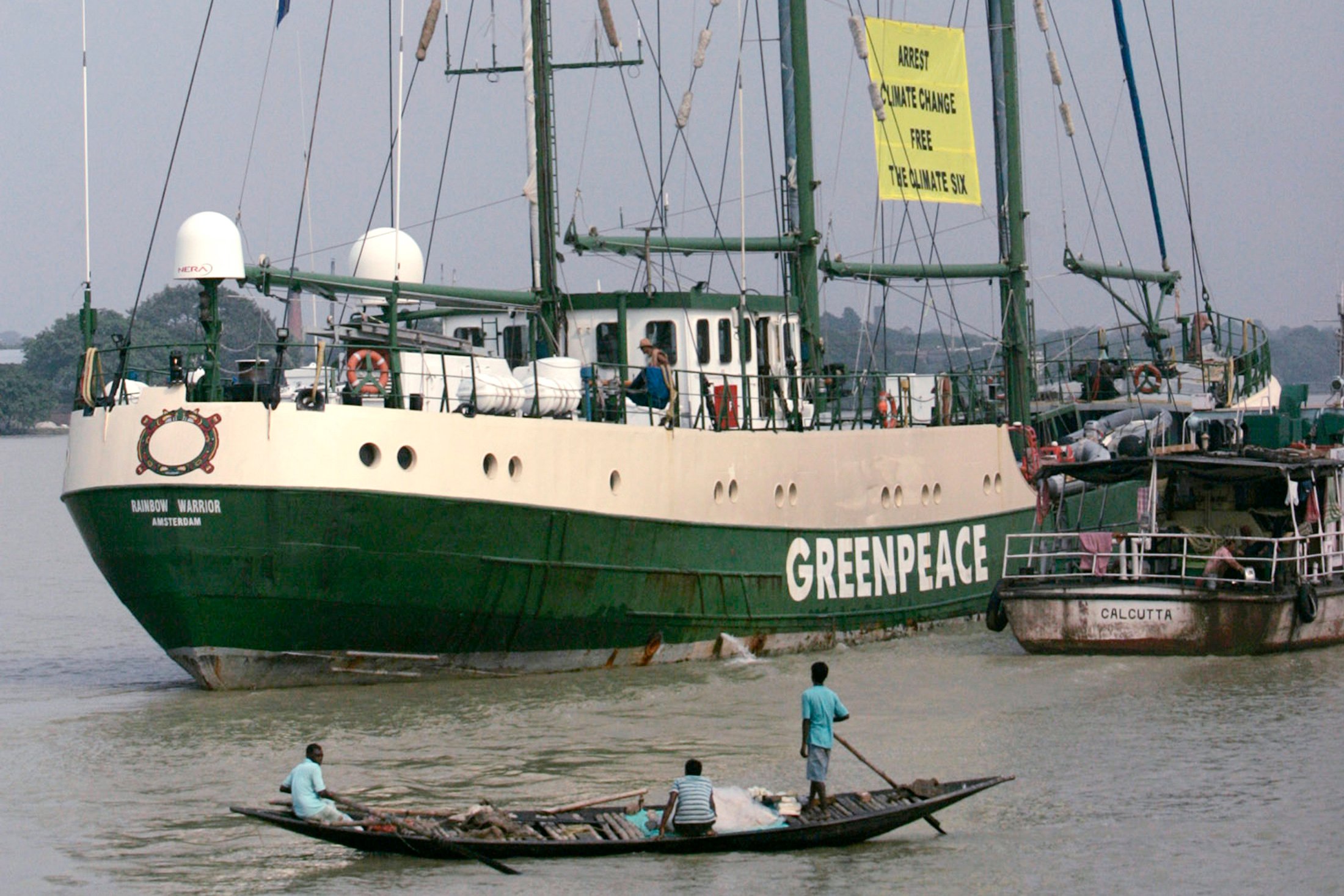 Fishermen watch the Green peace ship "Rainbow Warrior" sail on the river Hooghly in Kolkata