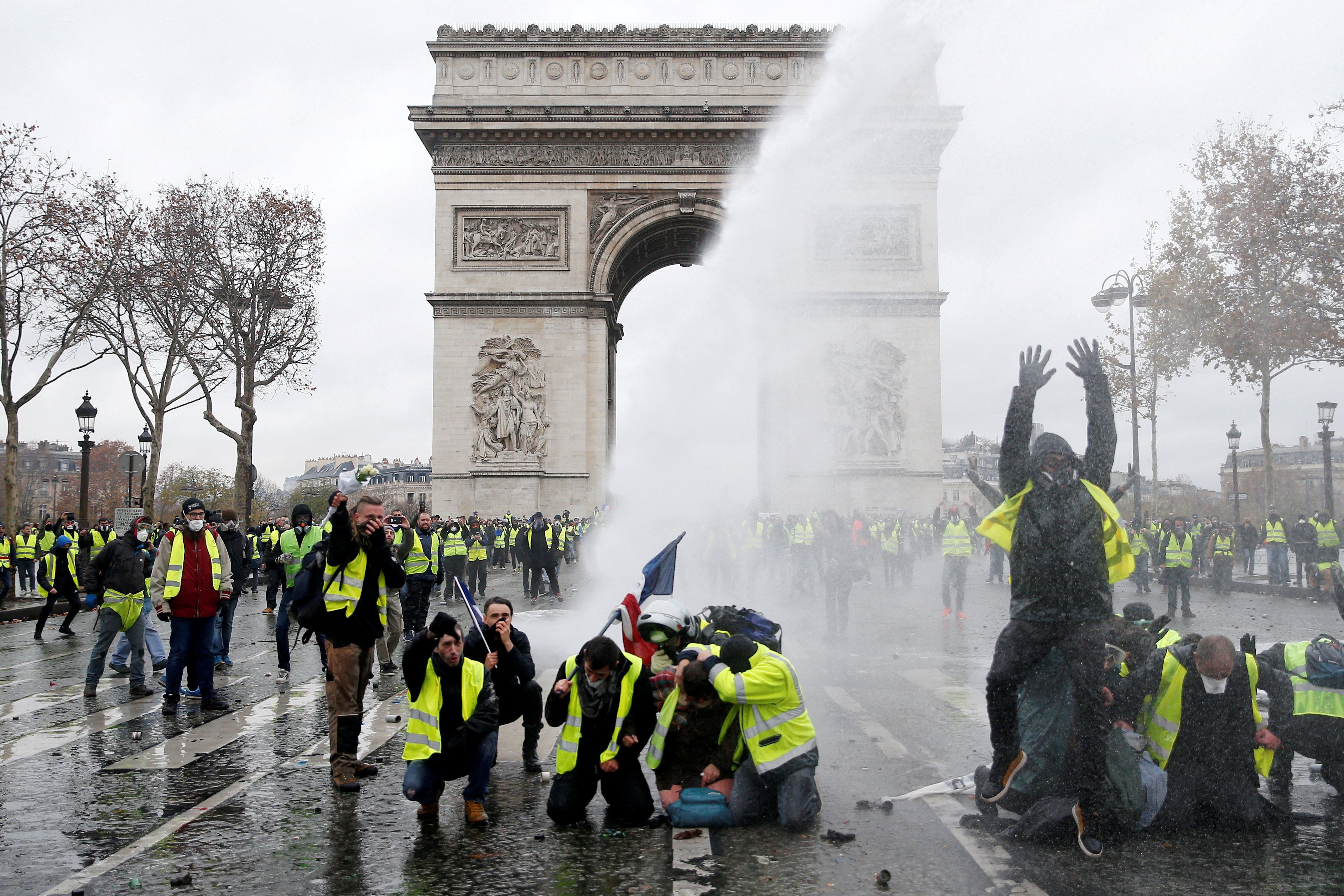 FILE PHOTO: Protesters wearing yellow vests, a symbol of a French drivers' protest against higher diesel taxes, stand up in front of a police water canon at the Place de l'Etoile near the Arc de Triomphe in Paris