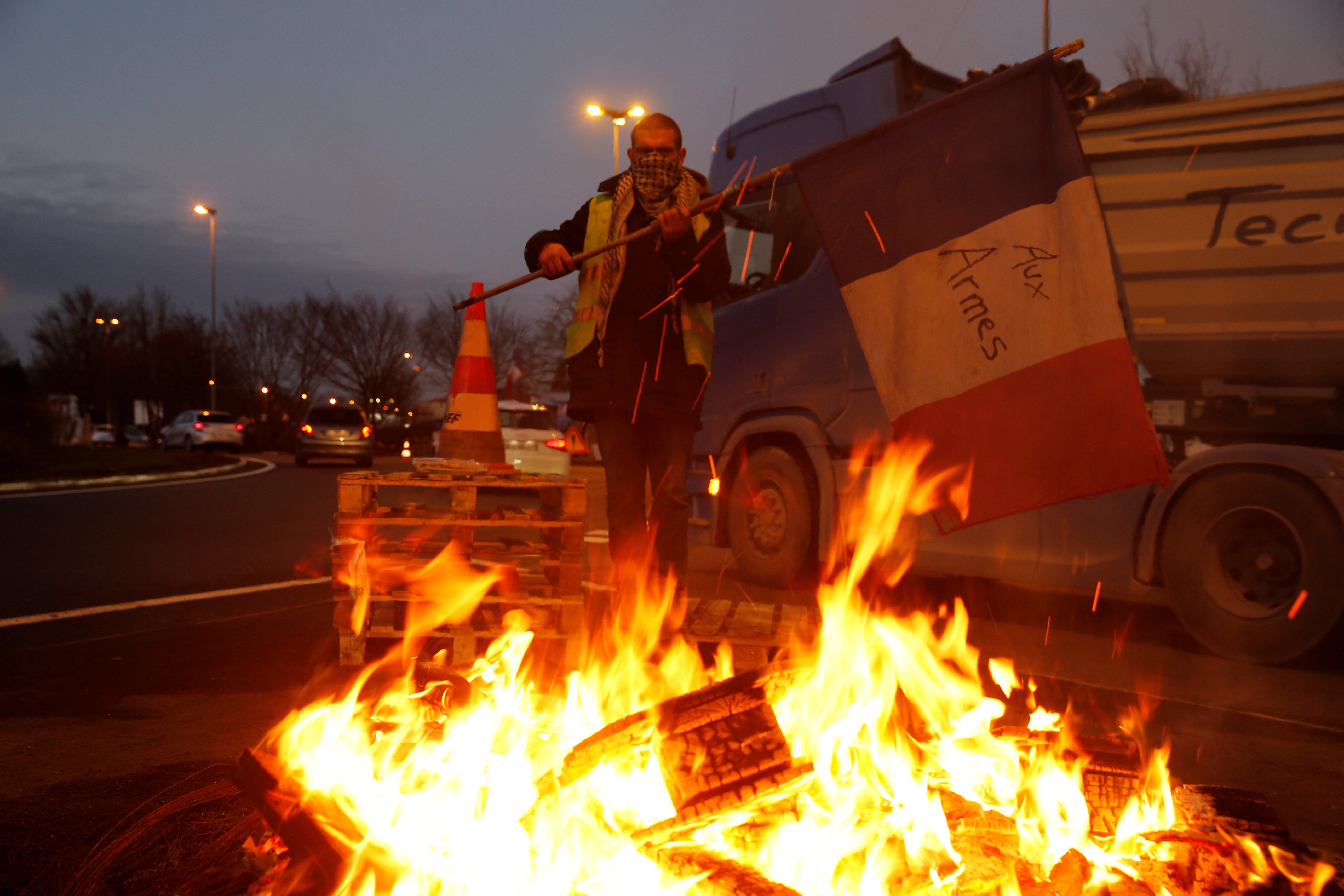A protester wearing a yellow vest, the symbol of a French drivers' protest against higher fuel prices, holds a flag at the approach to the A2 Paris-Brussels Motorway, in Fontaine-Notre-Dame