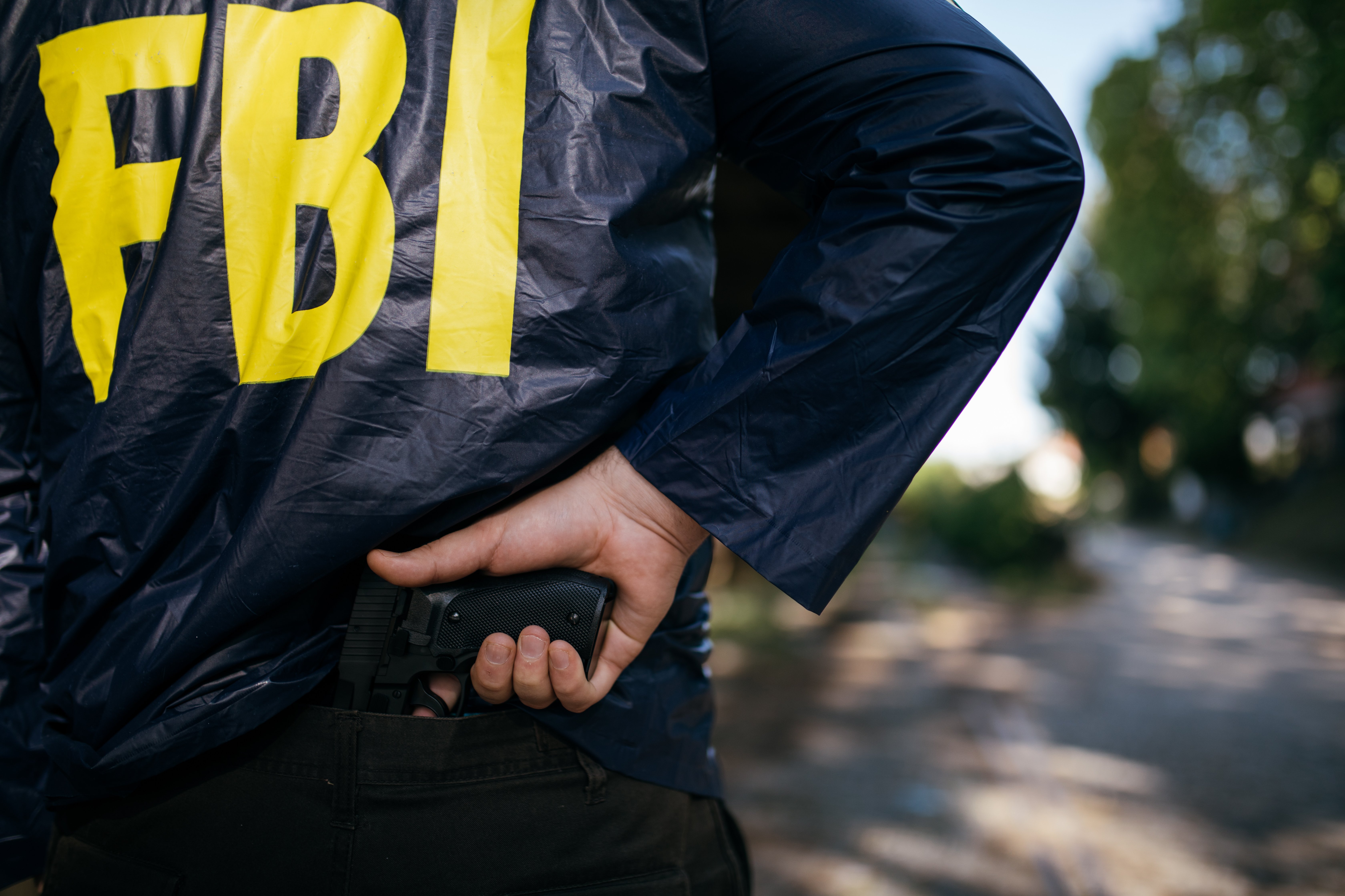 Cropped photo of FBI agent in action with a pistol, rear view/ Shutterstock, by Dzelat