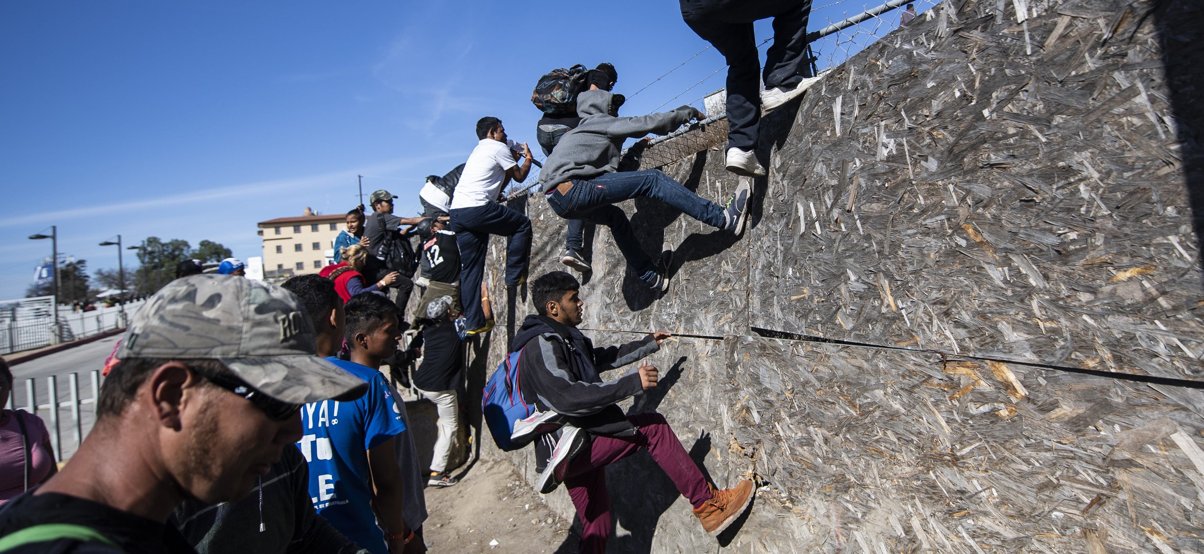 A group of Central American migrants -mostly from Honduras- get over a fence as they try to reach the US-Mexico border near the El Chaparral border crossing in Tijuana, Baja California State, Mexico, on November 25, 2018./ PEDRO PARDO/AFP/Getty Images