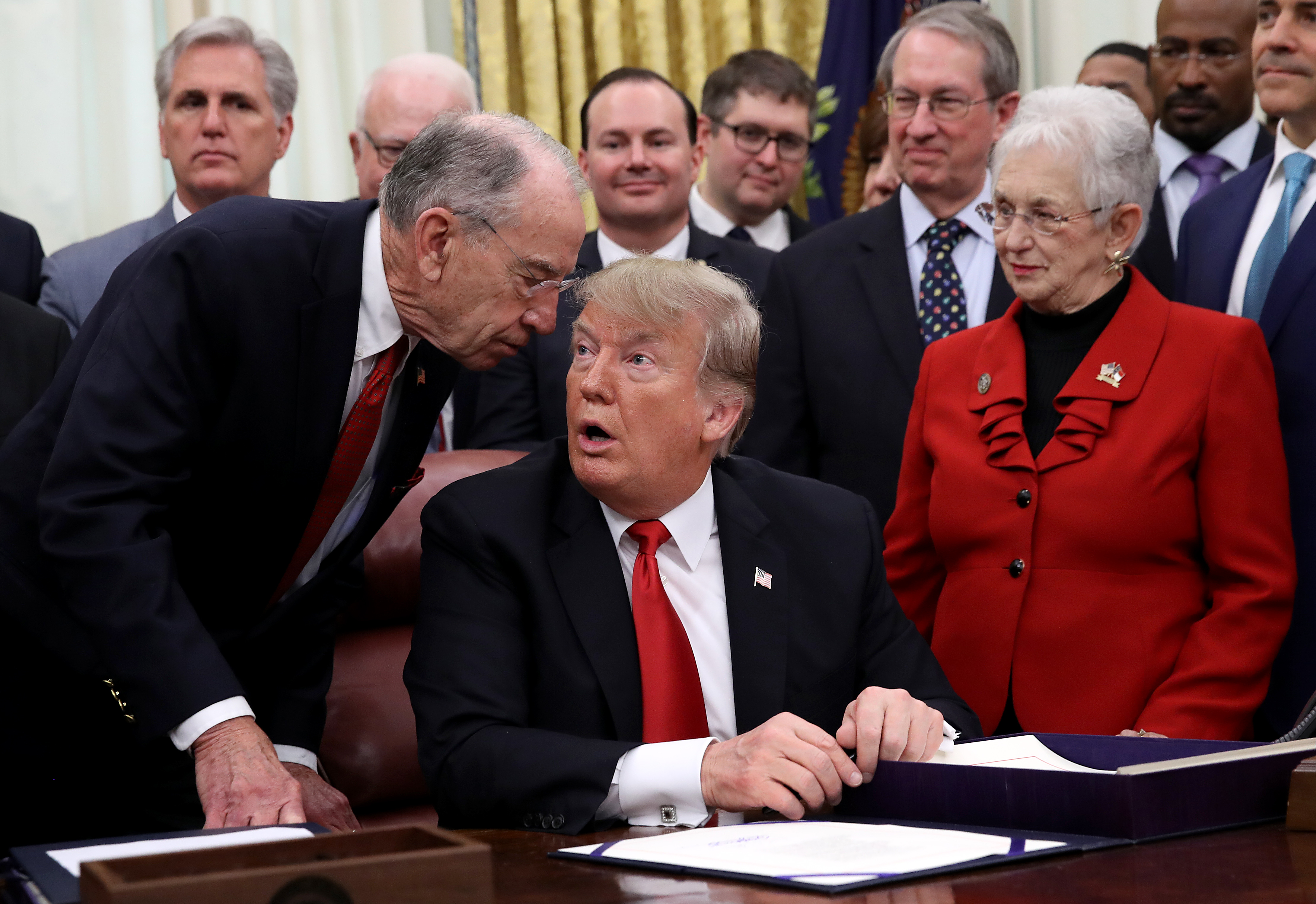 Senate Judiciary Committee Chairman Chuck Grassley (L) (R-IA) tells U.S. President Donald Trump that he needs to leave to cast a vote in the U.S. Senate during the signing ceremony for the First Step Act and the Juvenile Justice Reform Act in the Oval Office of the White House December 21, 2018 in Washington, DC. (Photo by Win McNamee/Getty Images)