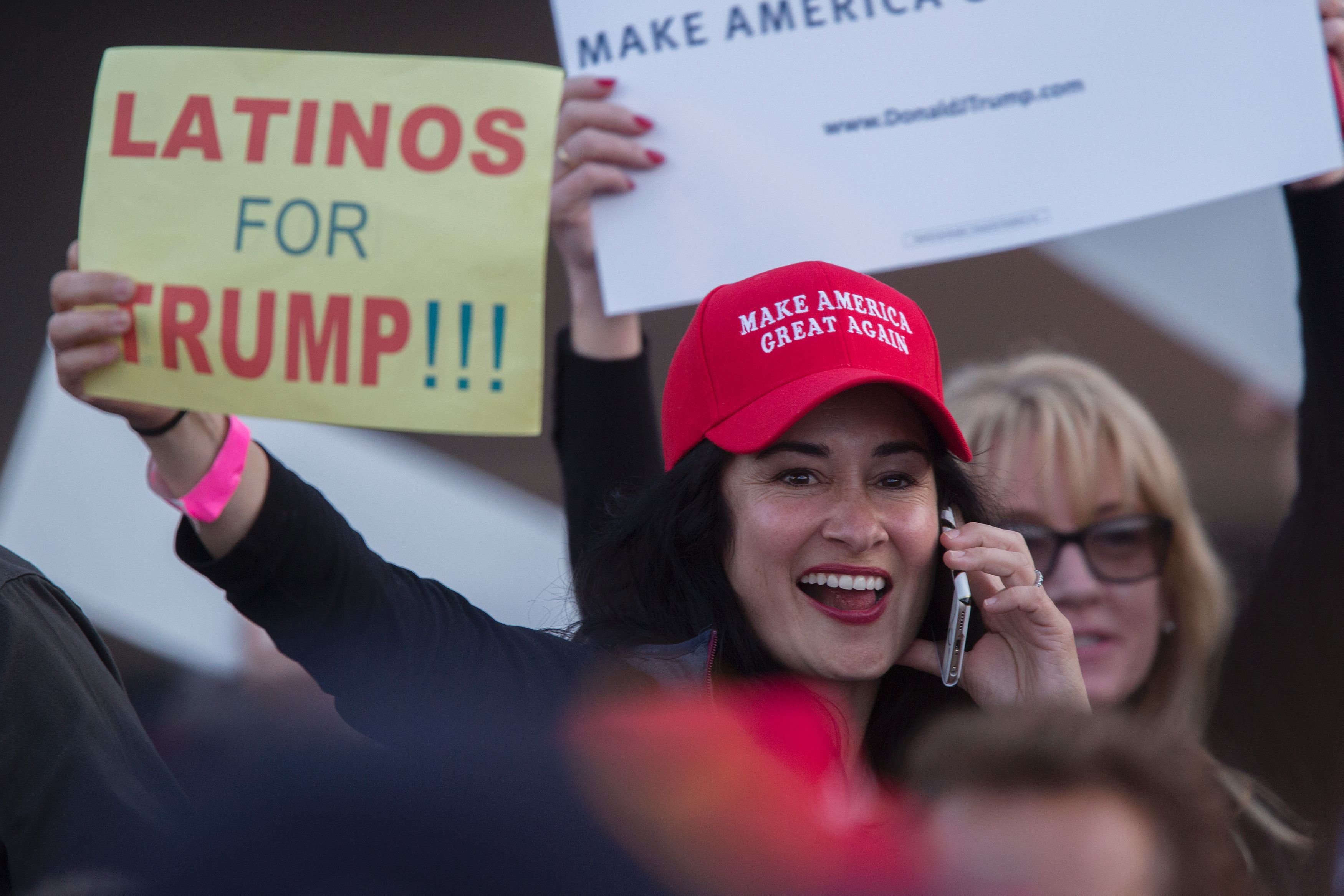 A woman holds a sign expressing Latino support for Republican presidential candidate Donald Trump at his campaign rally at the Orange County Fair and Event Center, April 28, 2016, in Costa Mesa, California. / AFP / DAVID MCNEW/ Getty Images