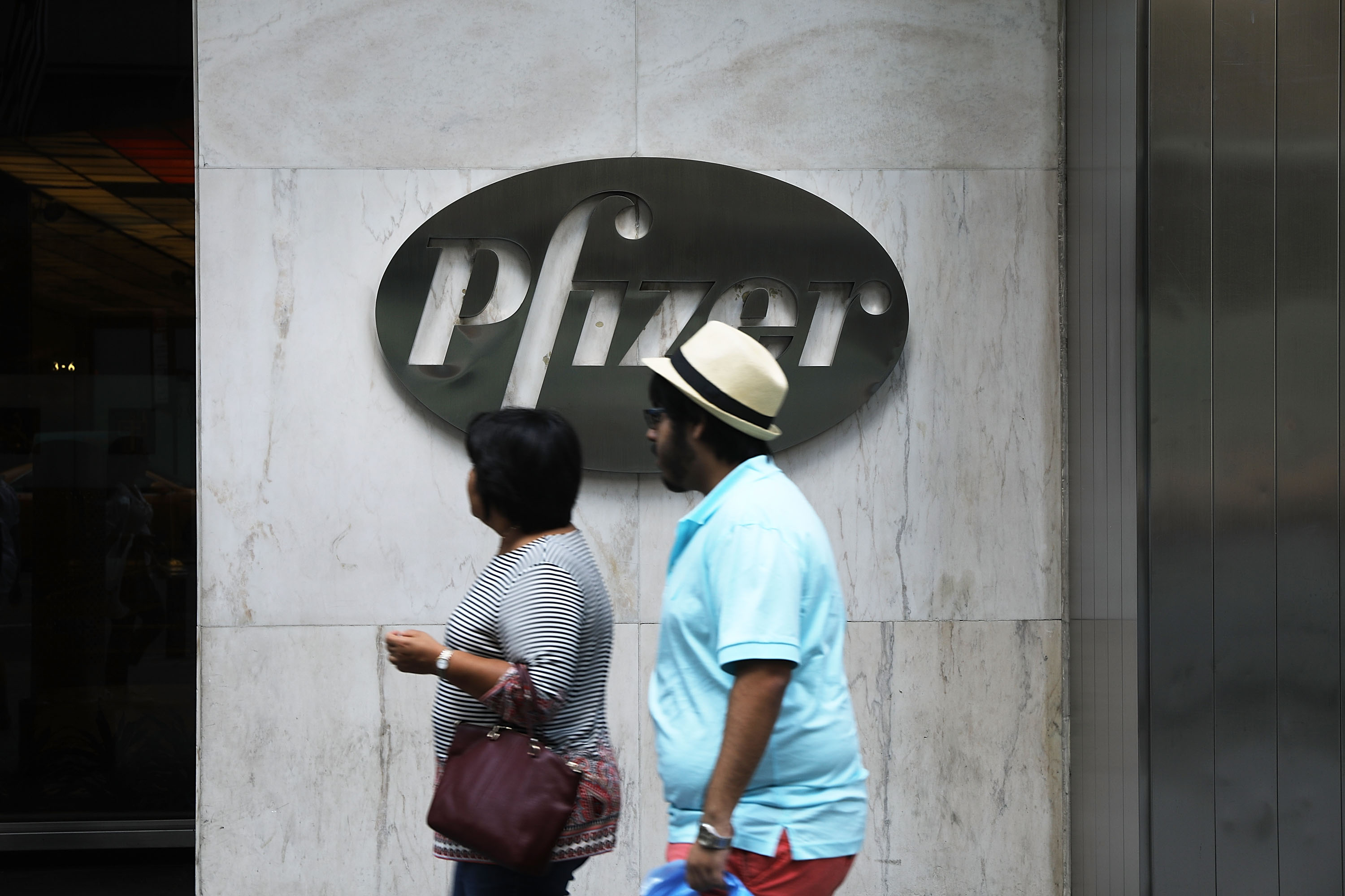 People pass the Pfizer headquarters in Manhattan on July 11, 2018 in New York City. (Photo by Spencer Platt/Getty Images)