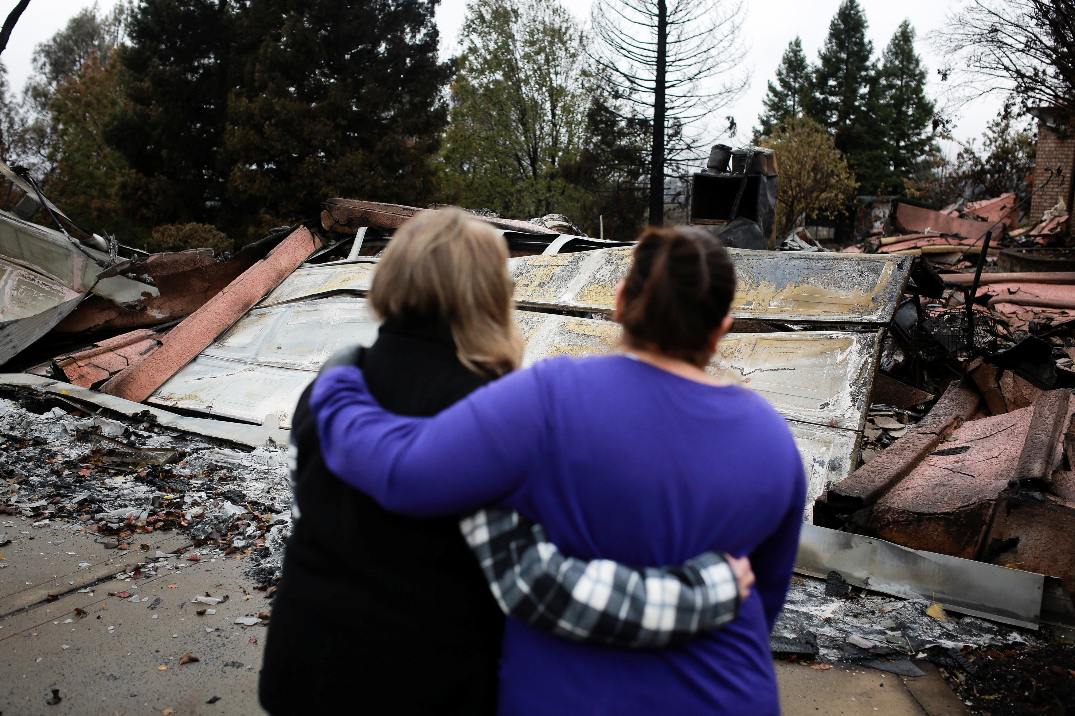 Irma Corona (R) comforts neighbor Gerryann Wulbern in front of the remains of Wulbern's home after the two returned for the first time since the Camp Fire in Paradise, California, U.S. November 22, 2018. REUTERS/Elijah Nouvelage