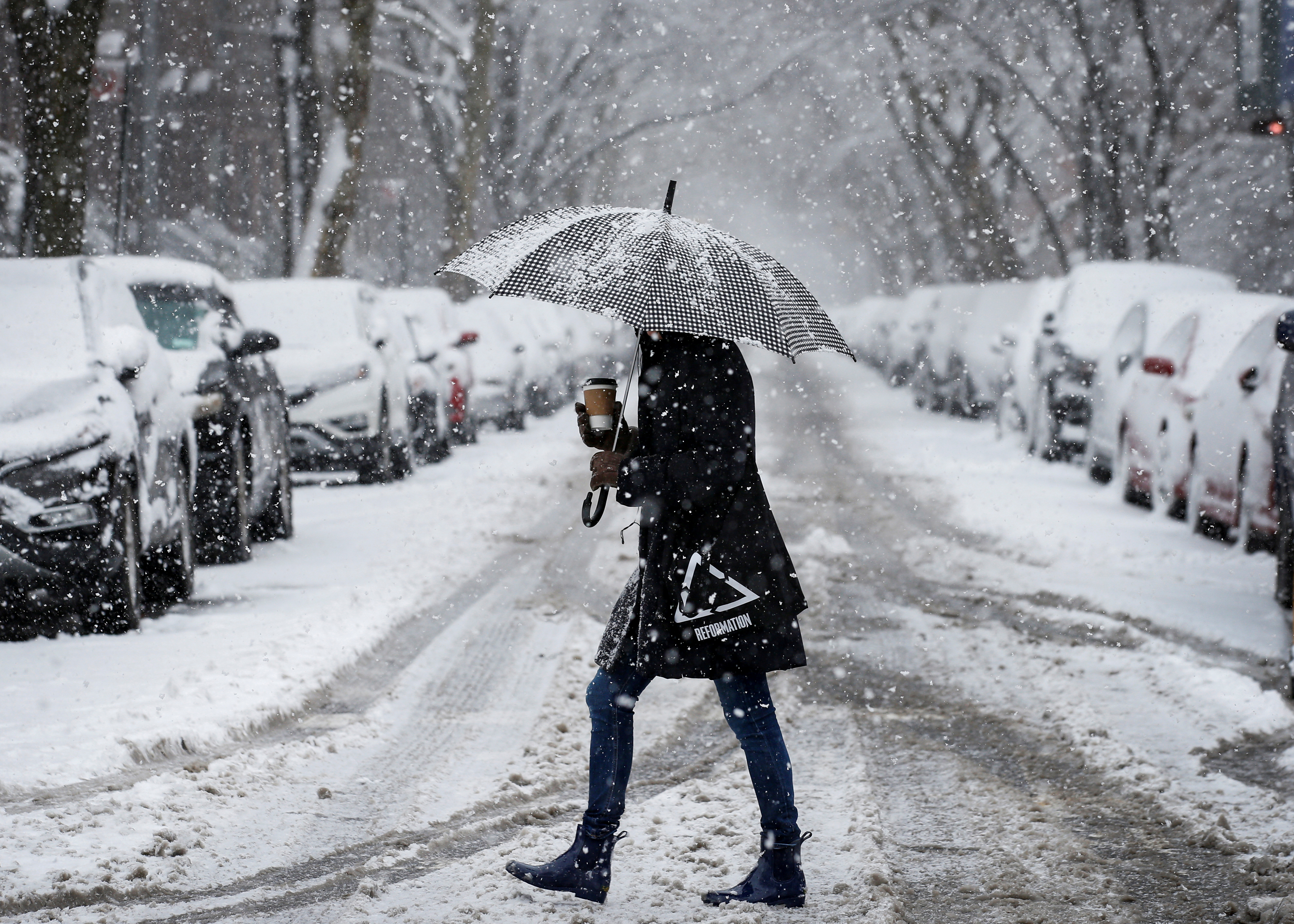 A woman walks in the snow during a winter nor'easter storm in the Brooklyn borough of New York