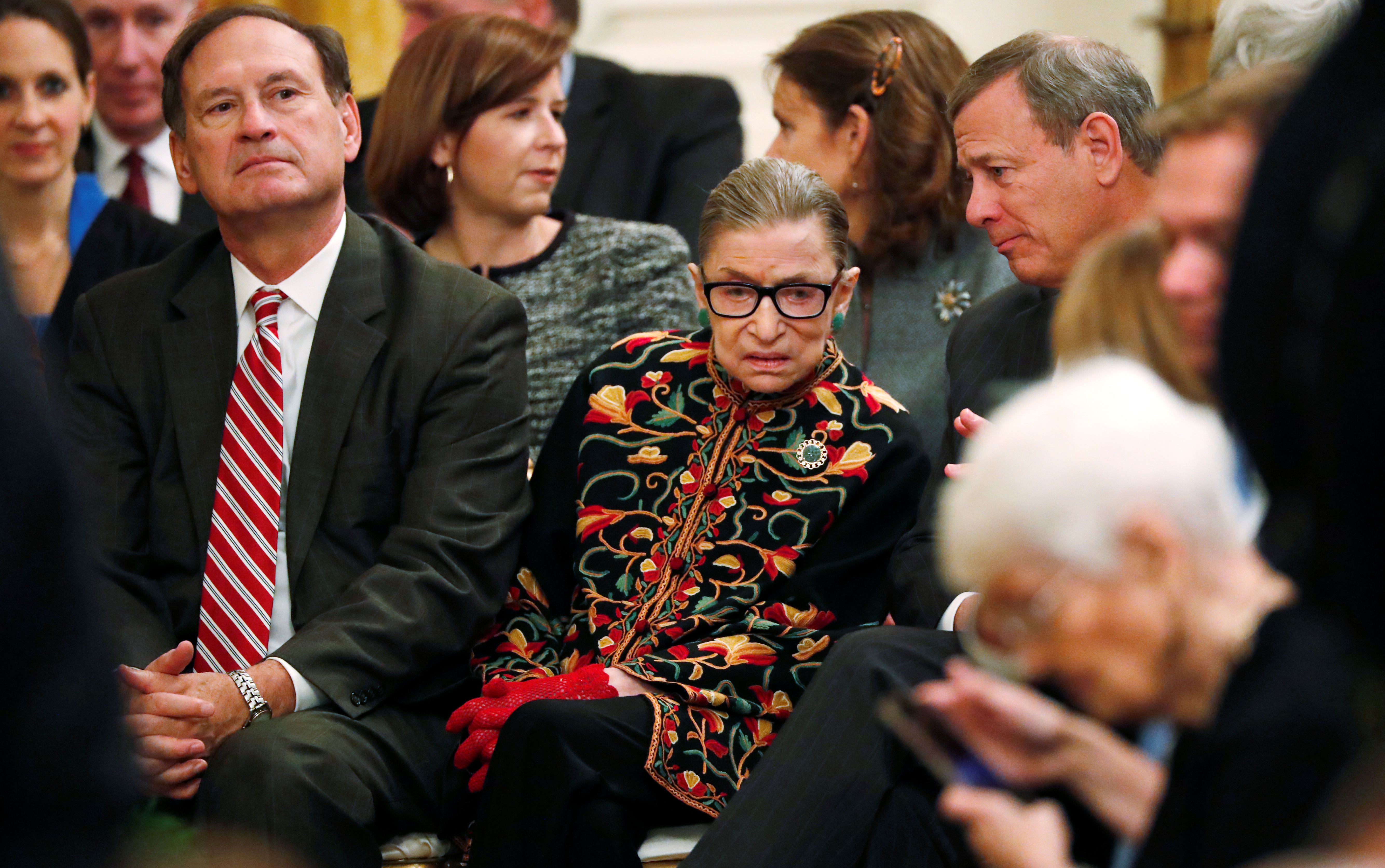 U.S. Supreme Court Associate Justice Ruth Bader Ginsburg talks with Chief Justice John Roberts as sits between Roberts and Associate Justice Samuel Alito as they attend a ceremony where President Donald Trump awarded the 2018 Presidential Medals of Freedom in the East Room of the White House in Washington, U.S. November 16, 2018. REUTERS/Leah Millis