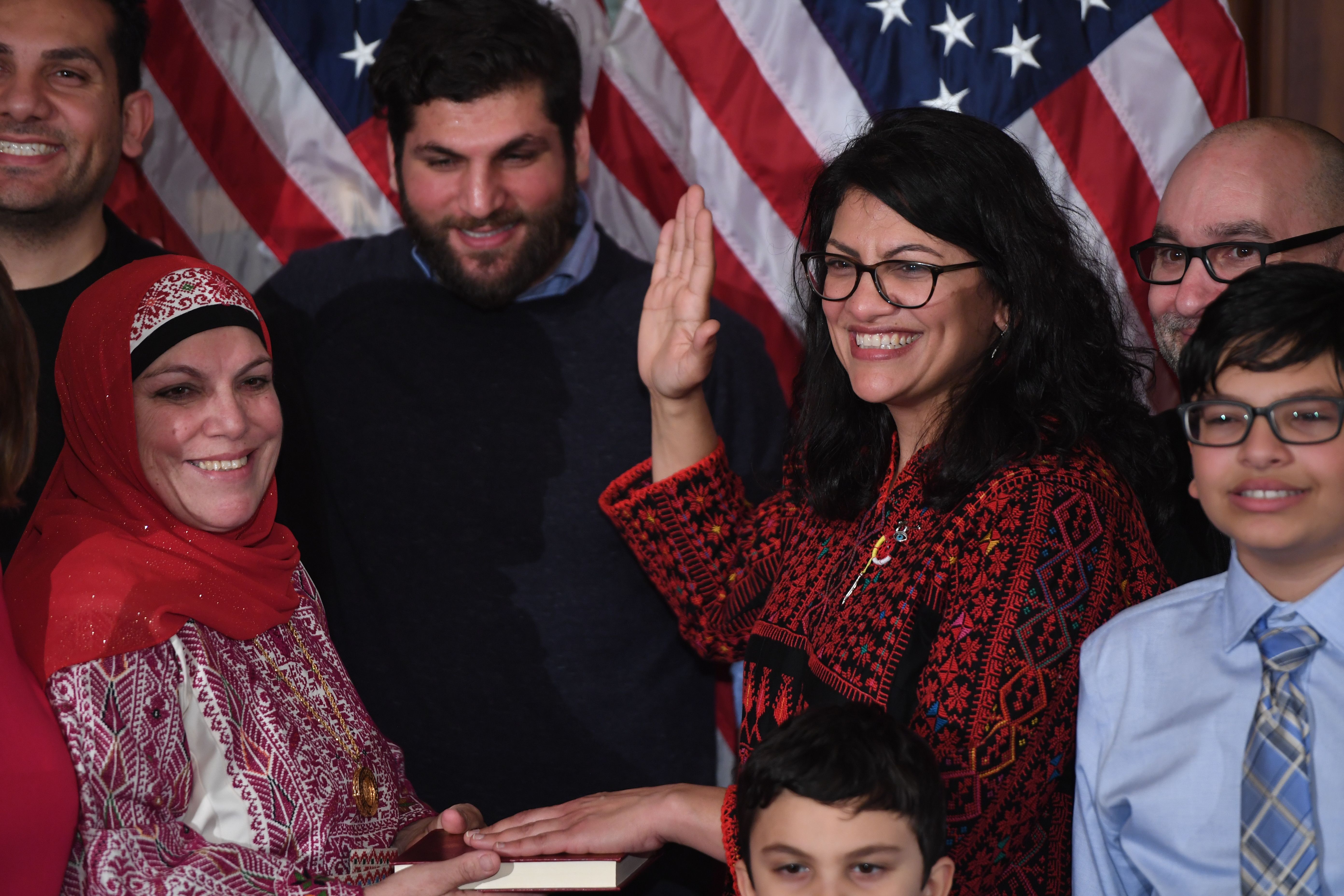 US House Representative Rashida Tlaib (D-MI), wearing a traditional Palestinian robe, takes the oath of office on Thomas Jefferson's English translated Quran, with family members present in a ceremonial swearing-in from Speaker of the House Nancy Pelosi (D-CA) (out of frame) at the start of the 116th Congress at the US Capitol in Washington, DC, January 3, 2019. (SAUL LOEB/AFP/Getty Images)