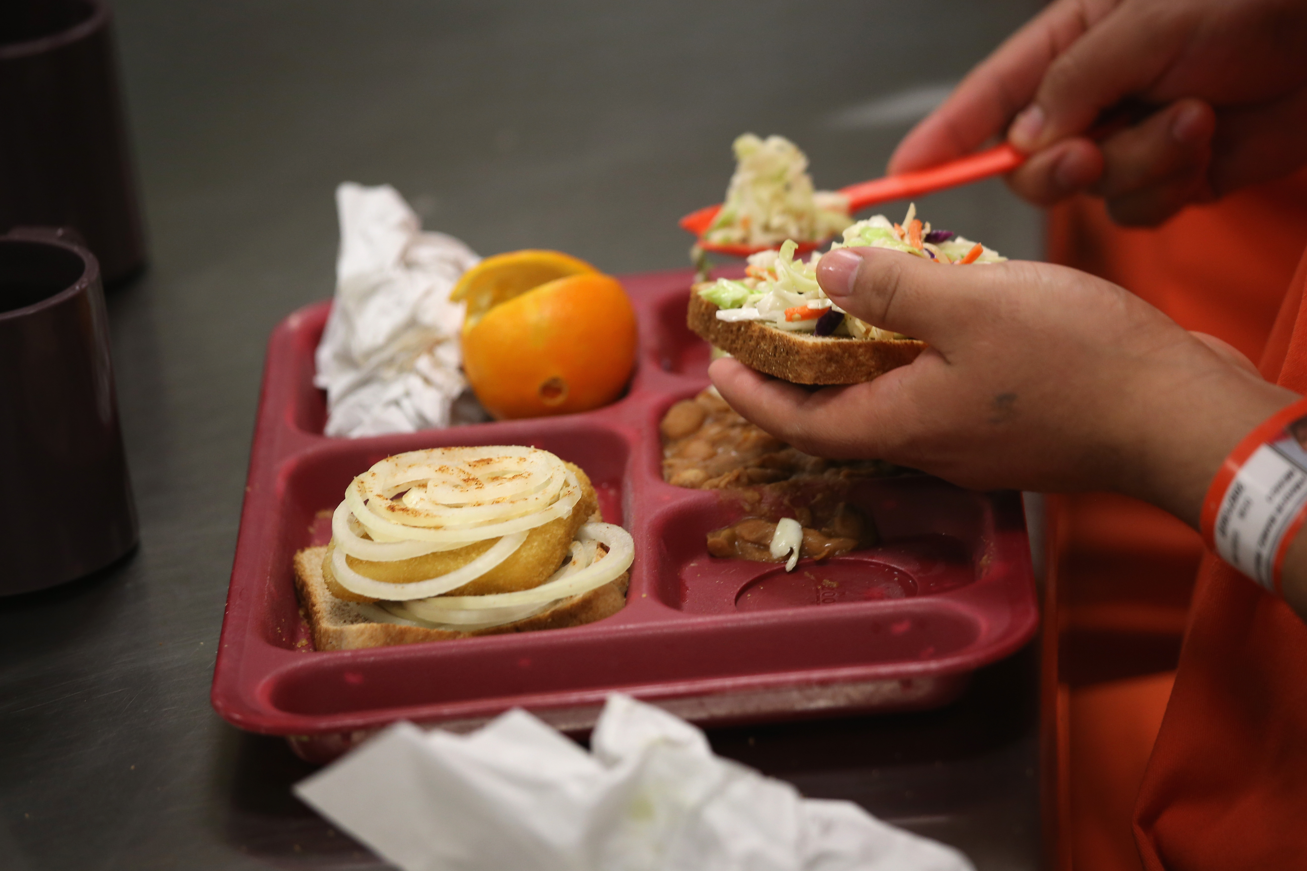 Immigrant detainees eat lunch, one of three meals a day, at the Adelanto Detention Facility on November 15, 2013 in Adelanto, California. (Photo by John Moore/Getty Images)