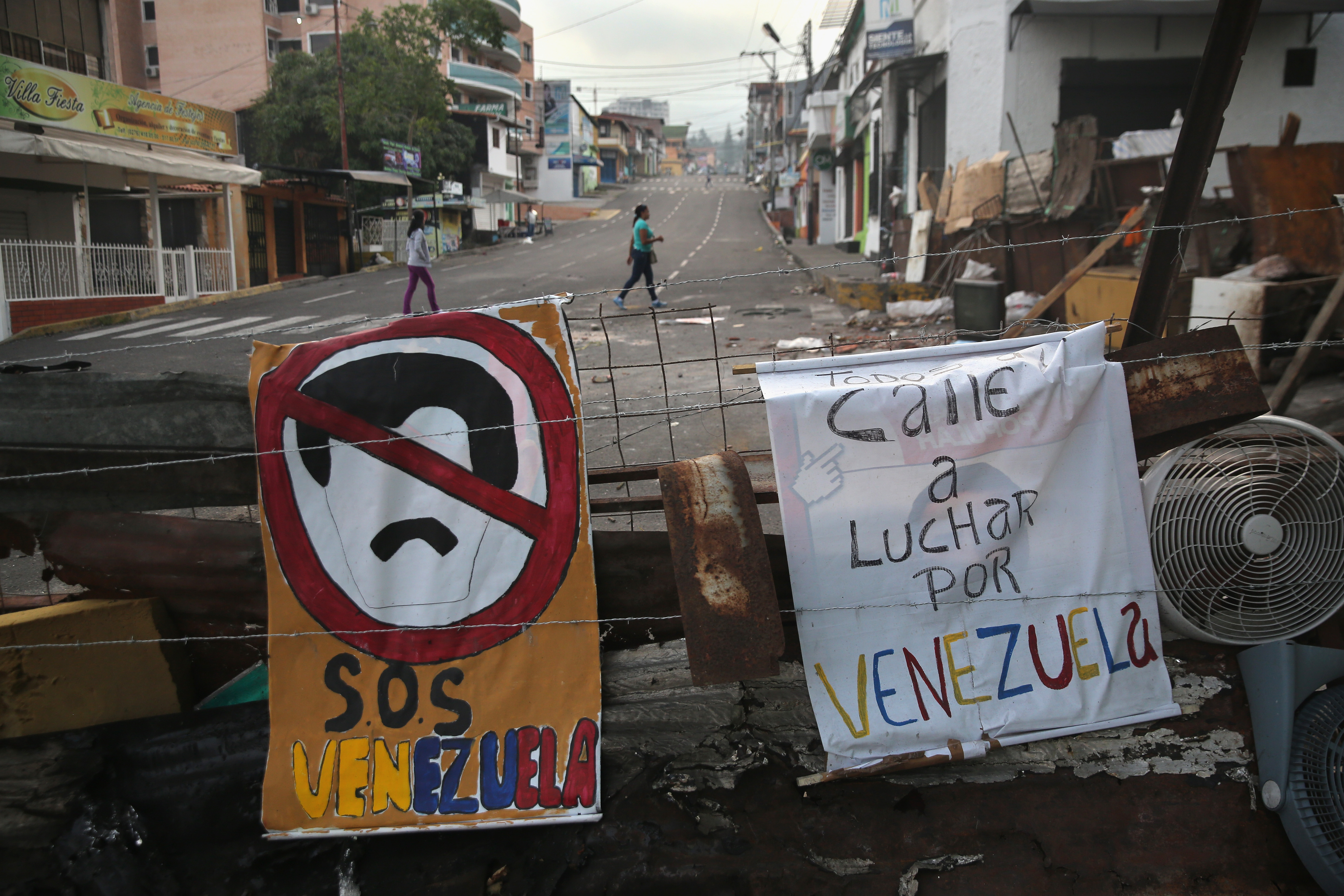 Women walk past protesters' barricades on March 8, 2014 in San Cristobal. (Photo by John Moore/Getty Images)