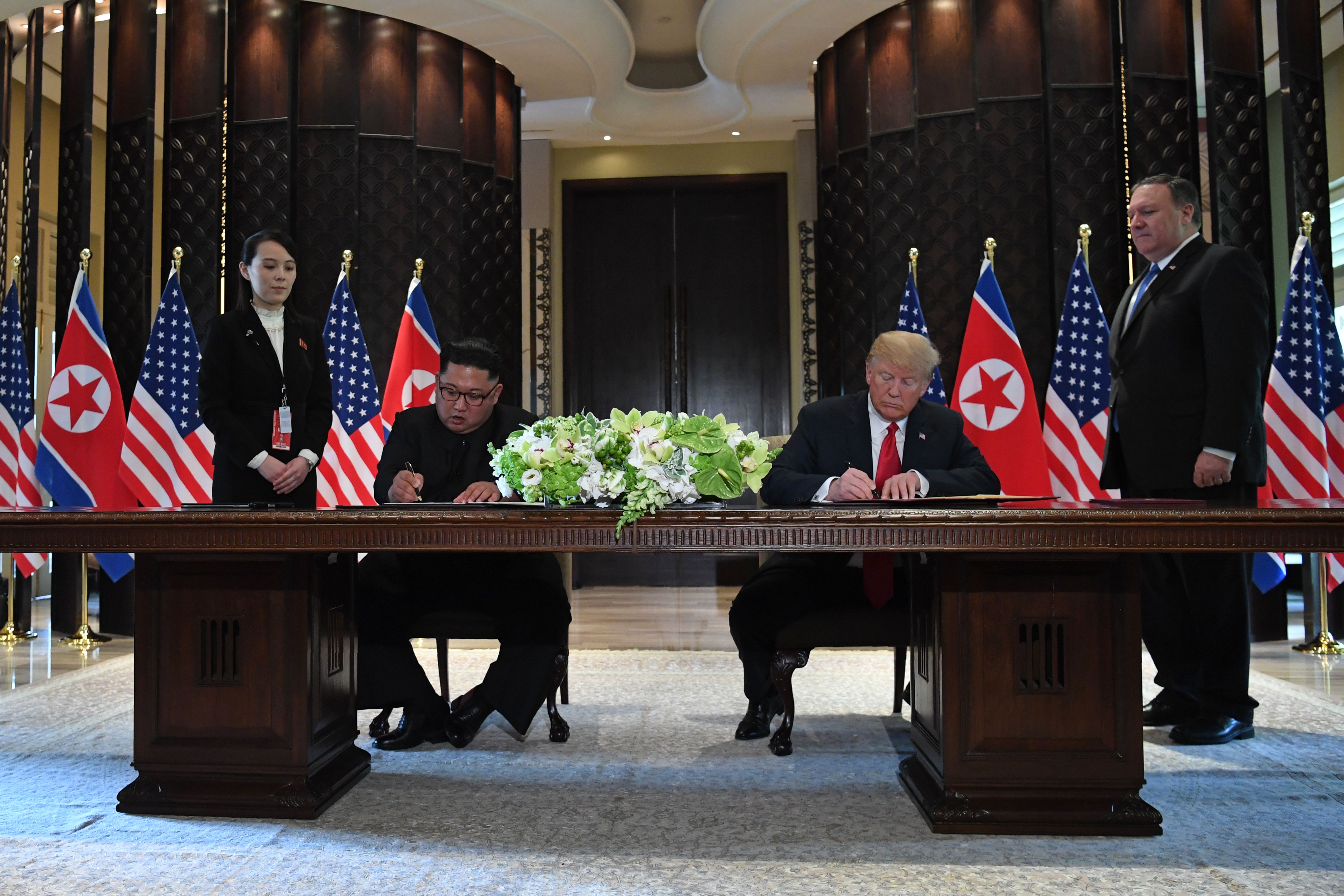 US President Donald Trump and North Korea's leader Kim Jong Un sign documents as US Secretary of State Mike Pompeo (R) and the North Korean leader's sister Kim Yo Jong (L) look on at a signing ceremony during their historic US-North Korea summit, at the Capella Hotel on Sentosa island in Singapore on June 12, 2018. (SAUL LOEB/AFP/Getty Images)