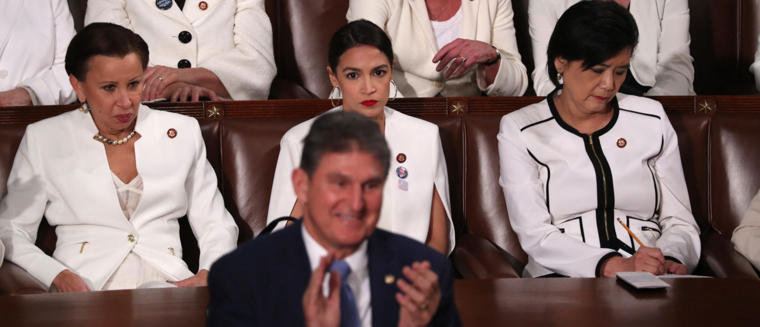 Democratic women of the U.S. House of Representatives, including Rep. Alexandria Ocasio-Cortez (D-NY) (C), remain in their seats as Senator Joe Manchin (D-WV) stands and applauds in front of them as U.S. President Donald Trump delivers his second State of the Union address. REUTERS/Jonathan Ernst
