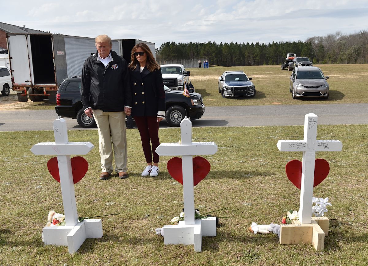 US President Donald Trump and First Lady Melania Trump stand before a row of crosses honoring 23 people who died in the storm outside Providence Baptist Church March 8, 2019 in Opelika, Alabama, during a tour of tornado-damaged areas in the southern US state. (Photo credit: KAMM/AFP/Getty Images)