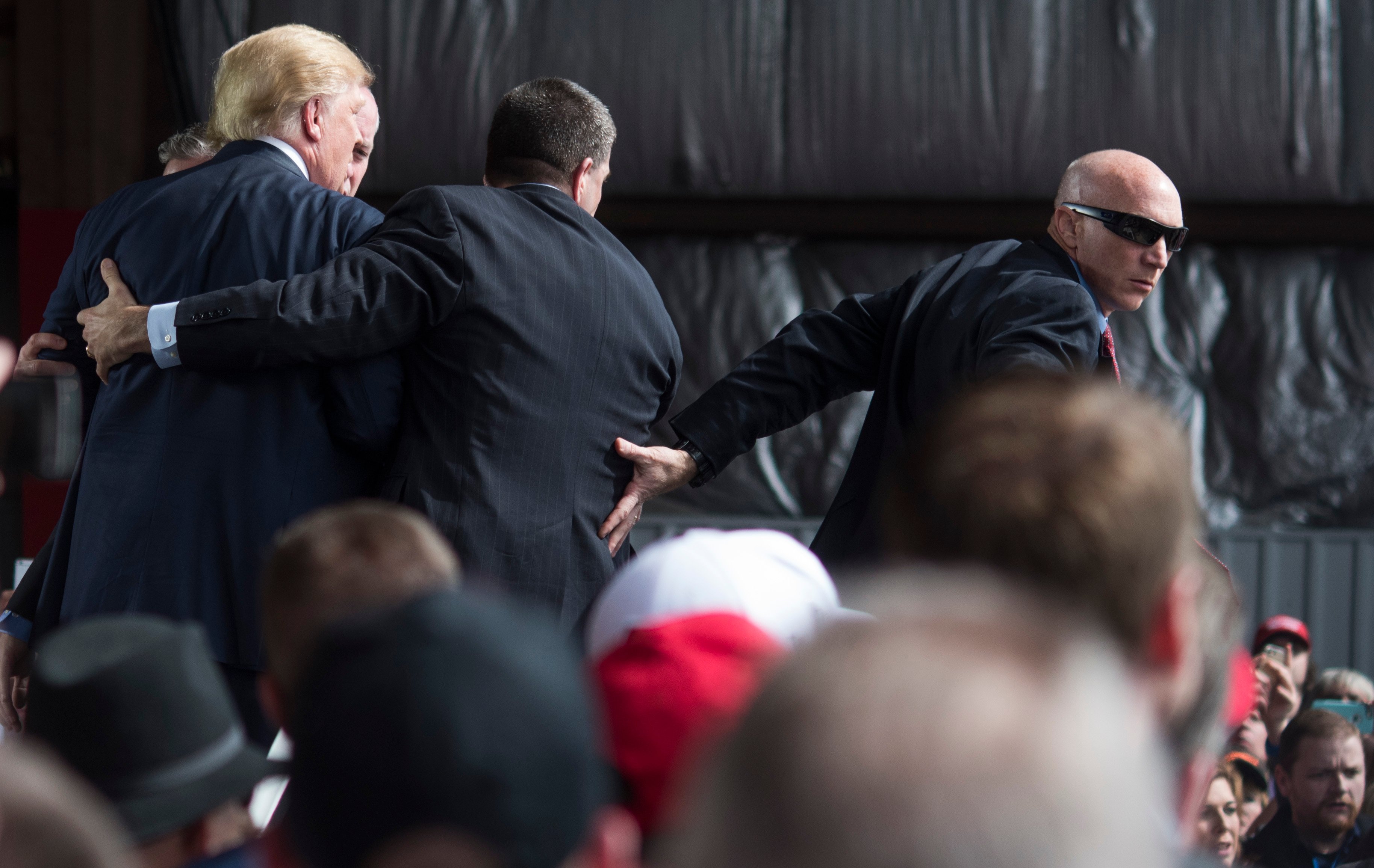 VANDALIA, OH - MARCH 12: Secret Service swarms around Republican Presidential candidate Donald Trump after a bottle was thrown on stage at a Campaign Rally on March 12, 2016 in Vandailia, Ohio. Today was the first rally after violence broke out in a Trump Rally in Chicago yesterday which canceled the rally. (Photo by Ty Wright/Getty Images)