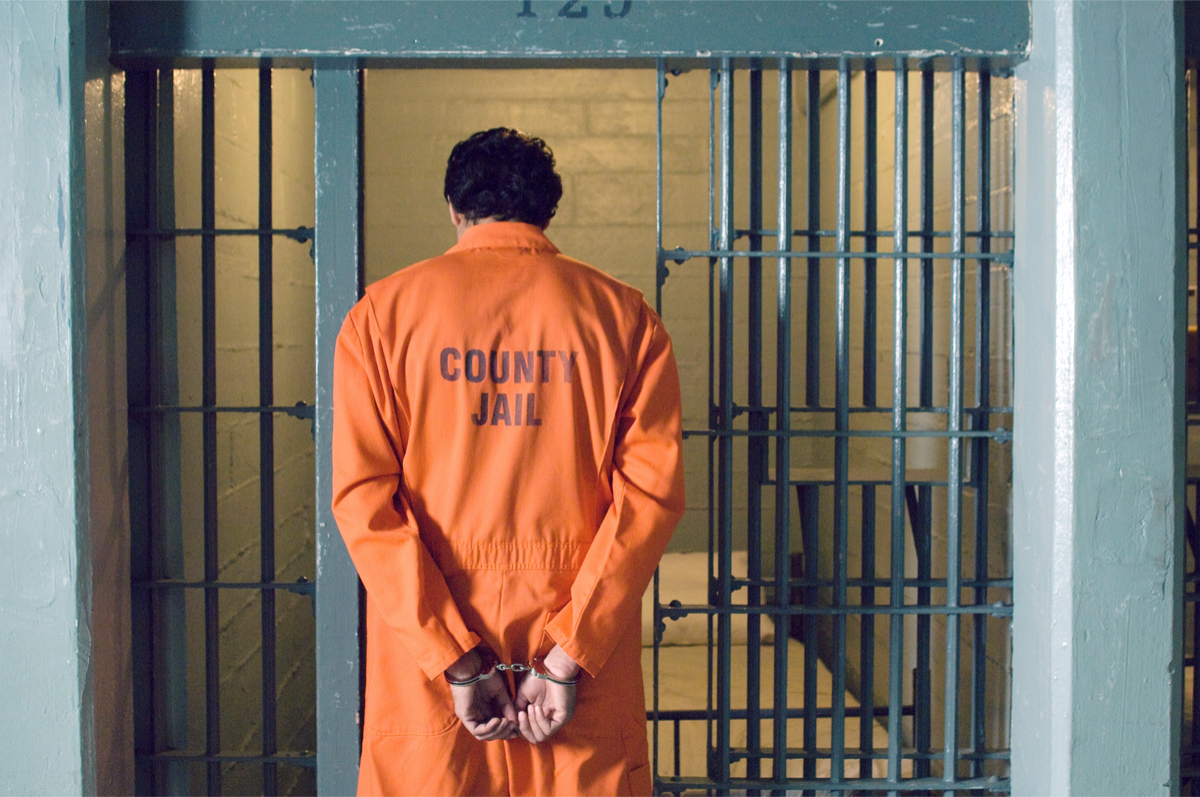 Handcuffed prisoner walks into jail cell. Shutterstock/sirtravelalot