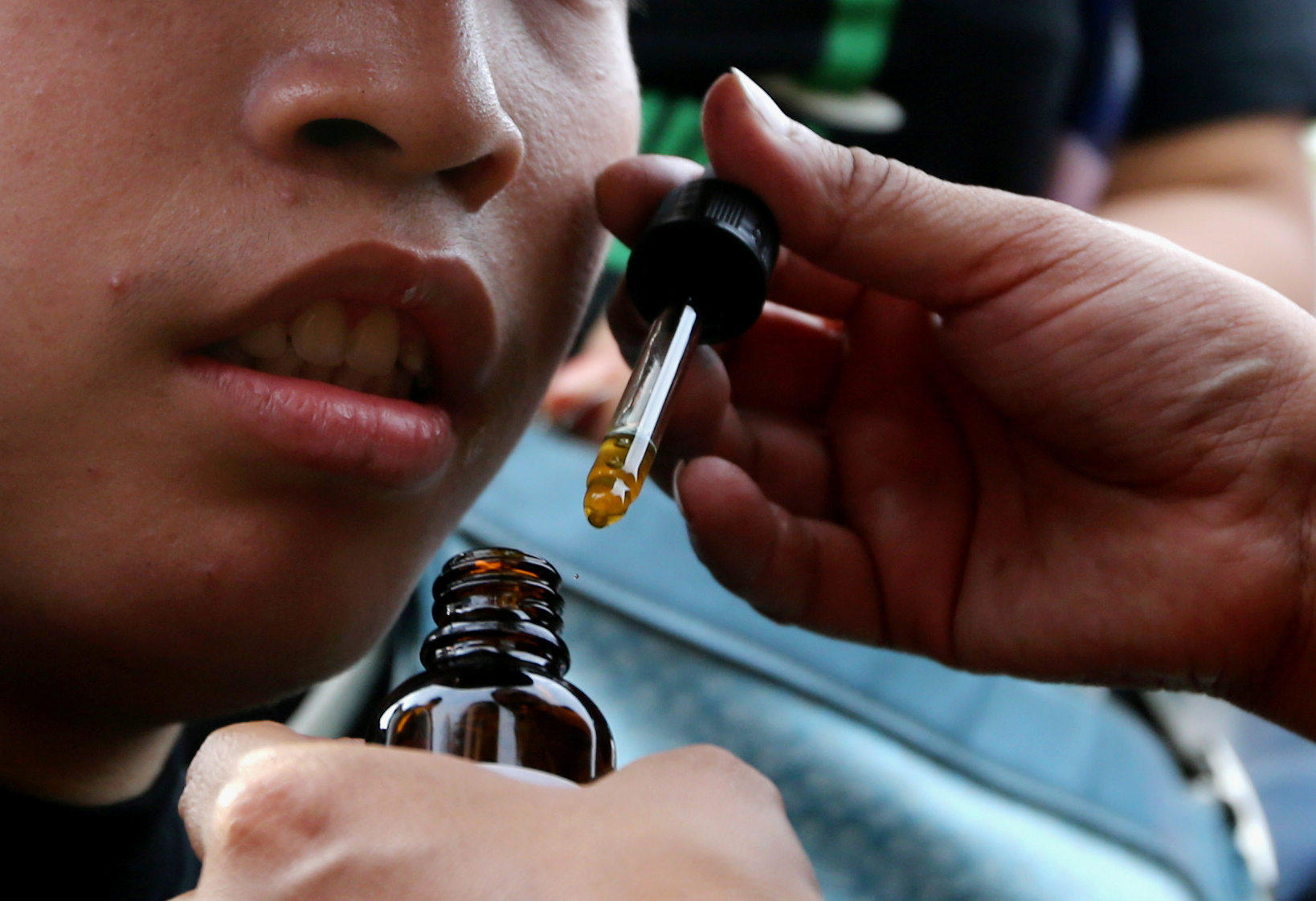 An adult gives a child a marijuana oil to soothe the symptoms of a disease during a protest for the legalization of medical marijuana in Lima, Peru March 1, 2017. REUTERS/Guadalupe Pardo - RC12FB21E7B0