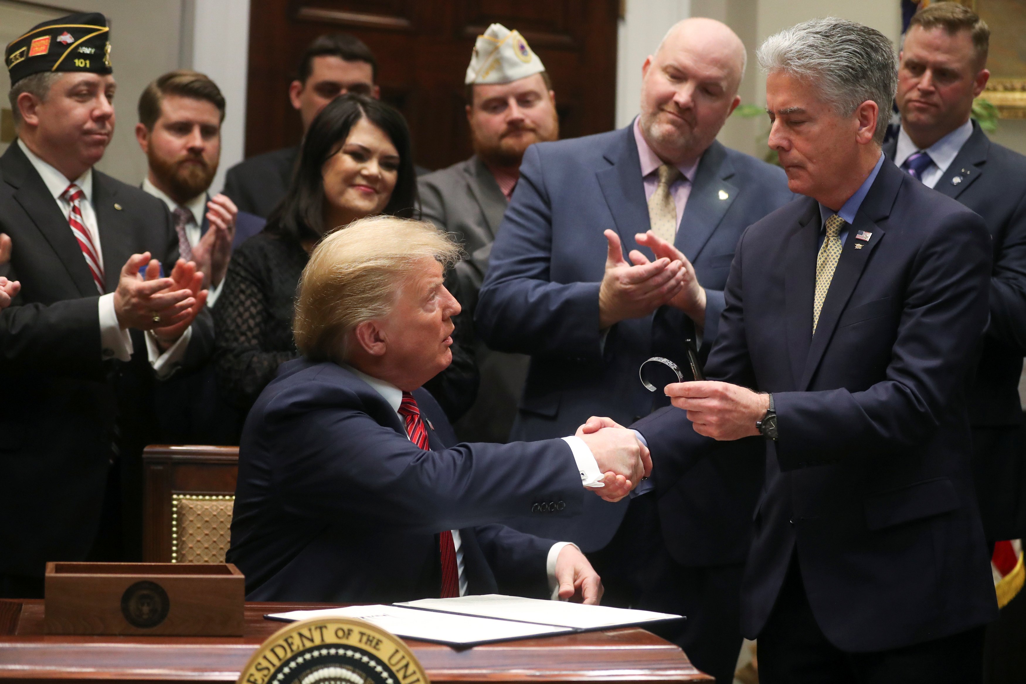 U.S. President Donald Trump shakes hands with former U.S. Navy SEAL and former Sergeant at Arms of the U.S. Senate Frank Larkin, whose son and fellow SEAL Ryan took his own life in April 2018, before Trump signed an executive order on veterans suicide prevention in the Roosevelt Room at the White House in Washington, U.S., March 5, 2019. REUTERS/Jonathan Ernst
