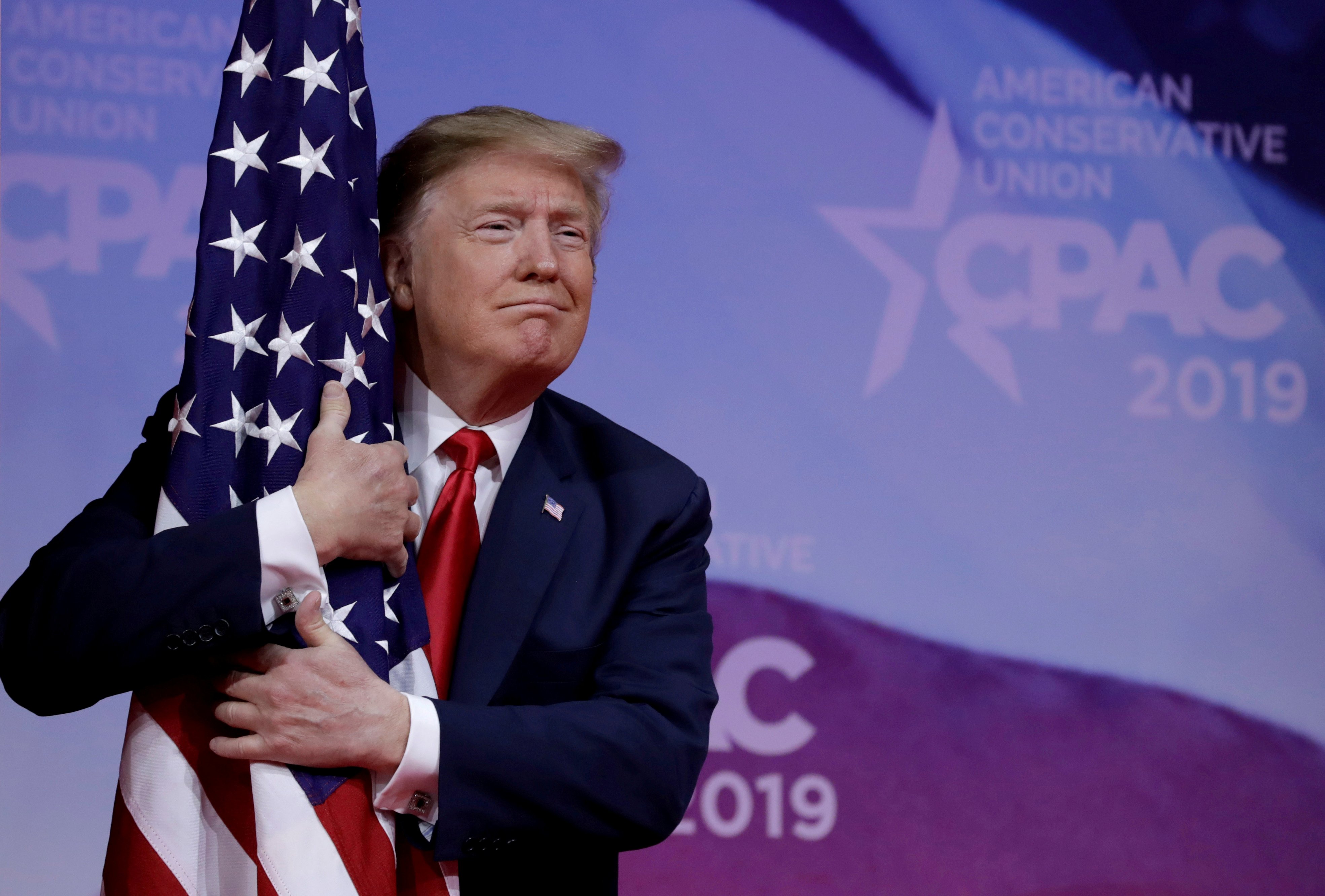 U.S. President Donald Trump hugs American flag at the Conservative Political Action Conference (CPAC) annual meeting at National Harbor near Washington, U.S., March 2, 2019. REUTERS/Yuri Gripas 