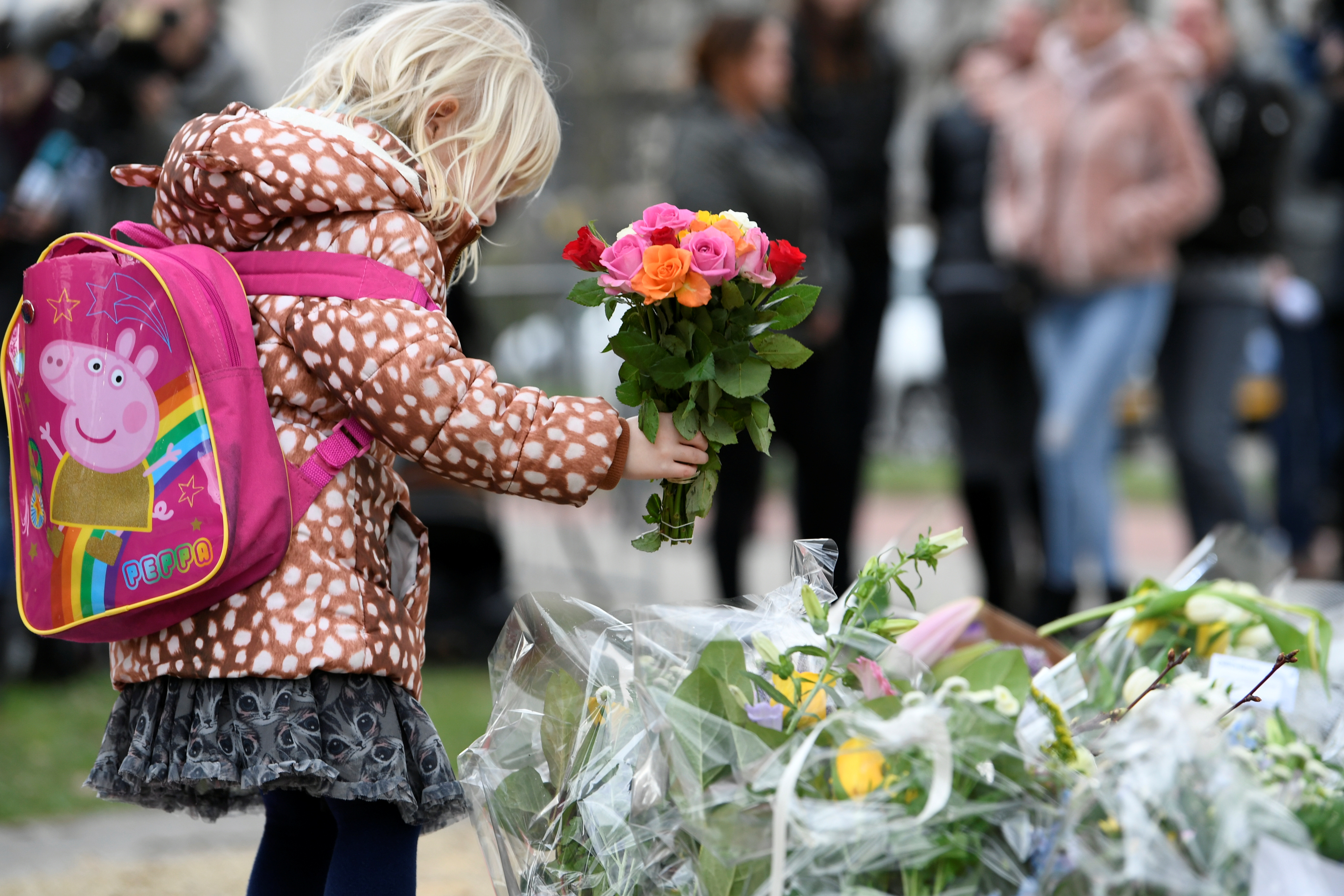 A child places flowers at a makeshift memorial at the site of a tram shooting in Utrecht, Netherlands March 19, 2019. REUTERS/Piroschka van de Wouw