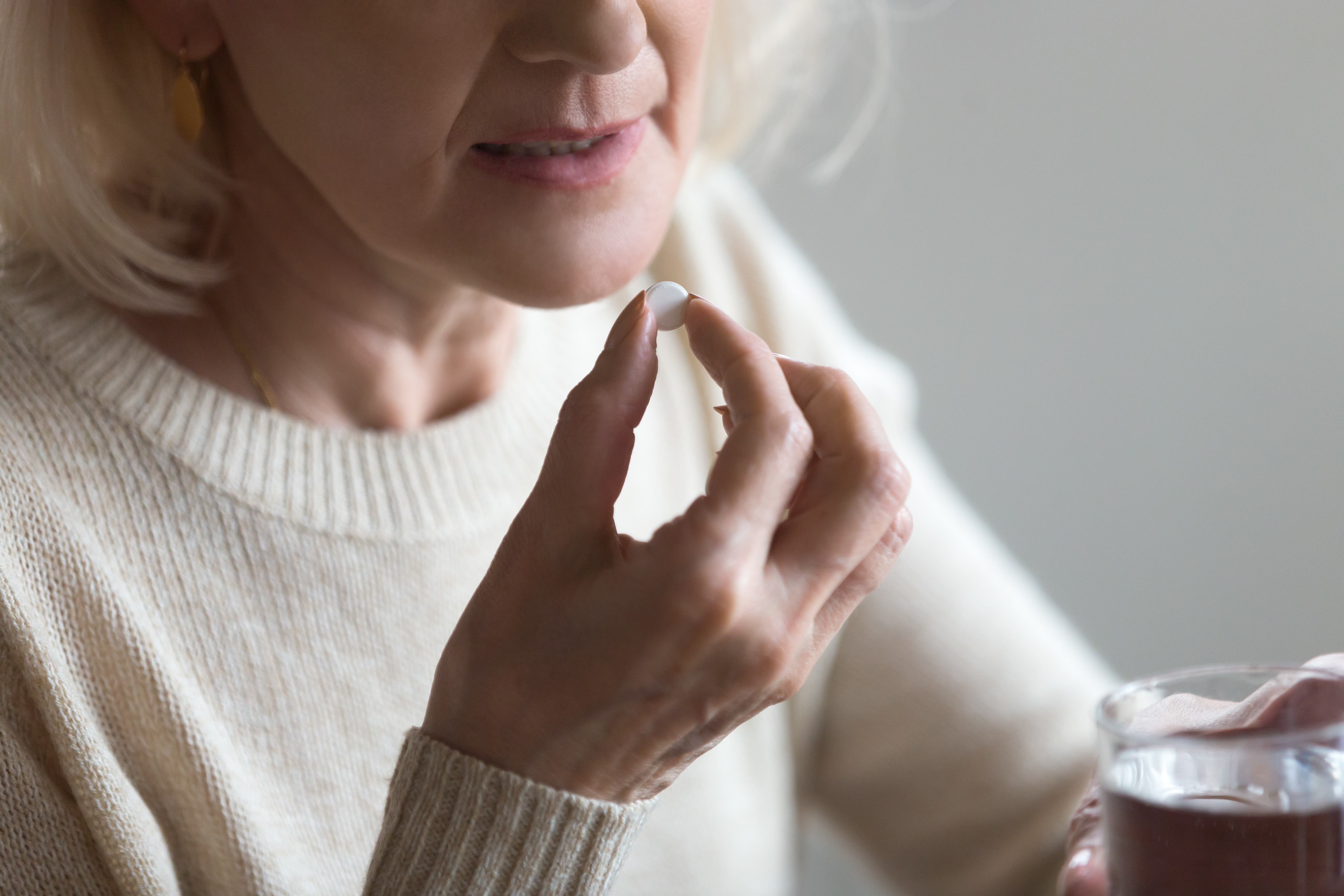 A woman takes a pill. Shutterstock image via user fizkes
