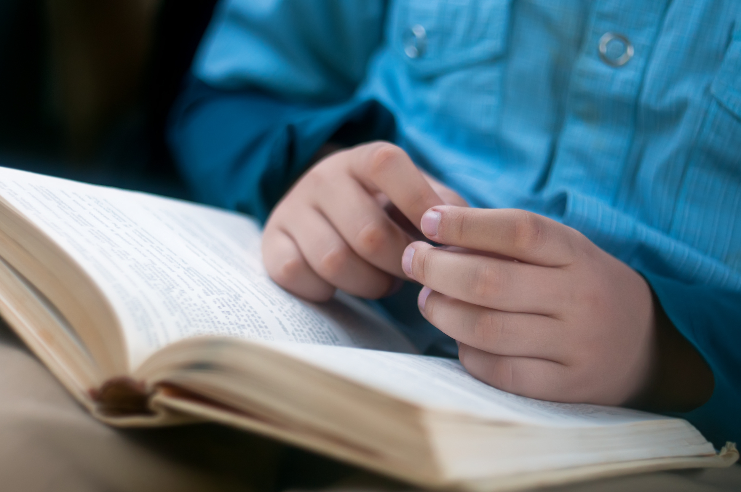 Child hands are on the open book (Yuliya Evstratenko/Shutterstock)