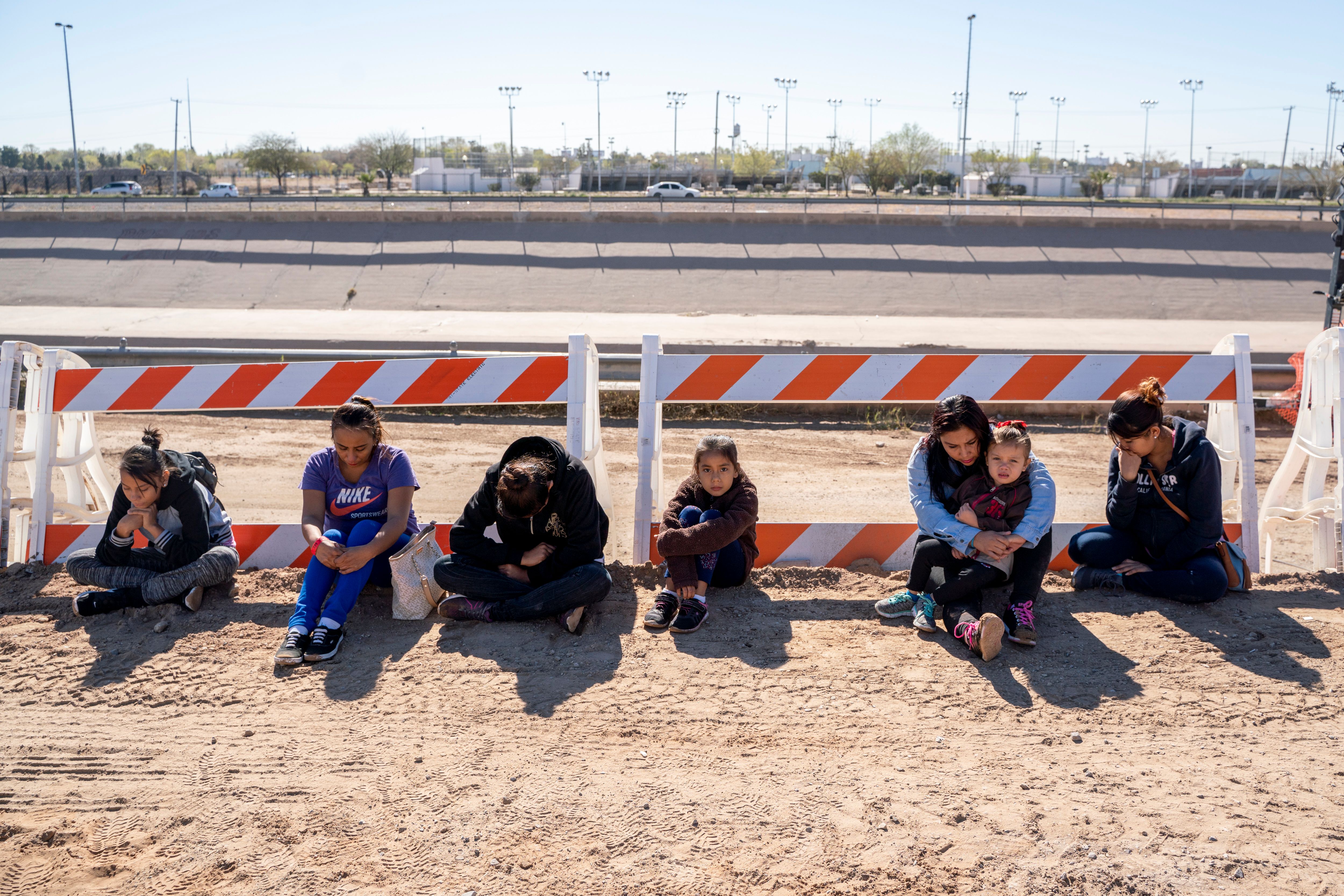 Salvadoran migrants wait for a transport to arrive after turning themselves into US Border Patrol by border fence under construction in El Paso, Texas on March 19, 2019. - Speaking of an "invasion" of illegal immigrants and criminals, US President Donald Trump last week signed the first veto of his presidency, overriding congressional opposition to secure emergency funding to build a wall on the Mexican border, the signature policy of his administration. (Photo by PAUL RATJE/AFP/Getty Images)