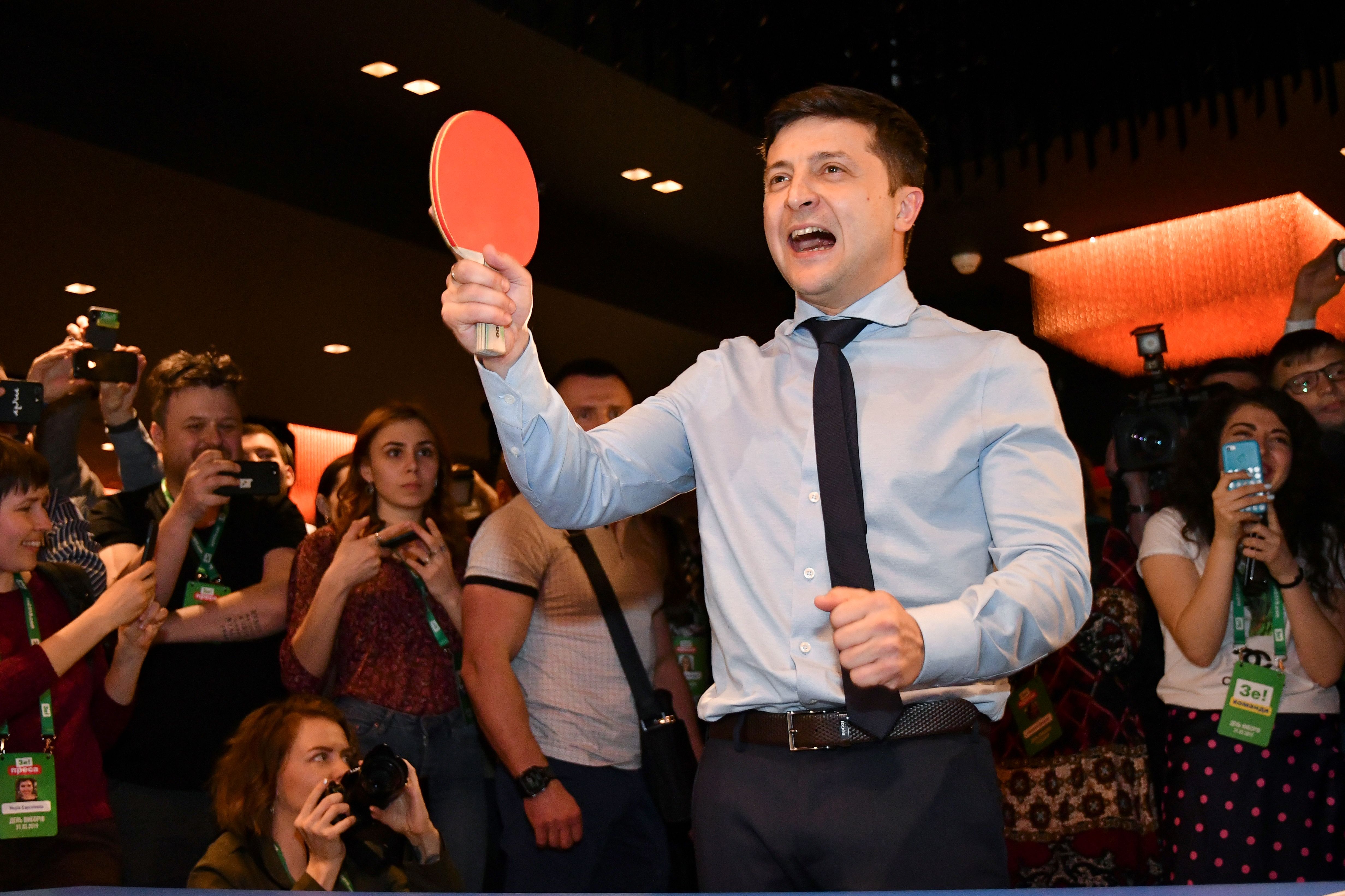 Ukrainian comic actor, showman and presidential frontrunner Volodymyr Zelensky surrounded by cameramen and photographers plays table tennis with a journalist ahead of the provisional results at the headquarter in Kiev on March 31, 2019. (GENYA SAVILOV/AFP/Getty Images)