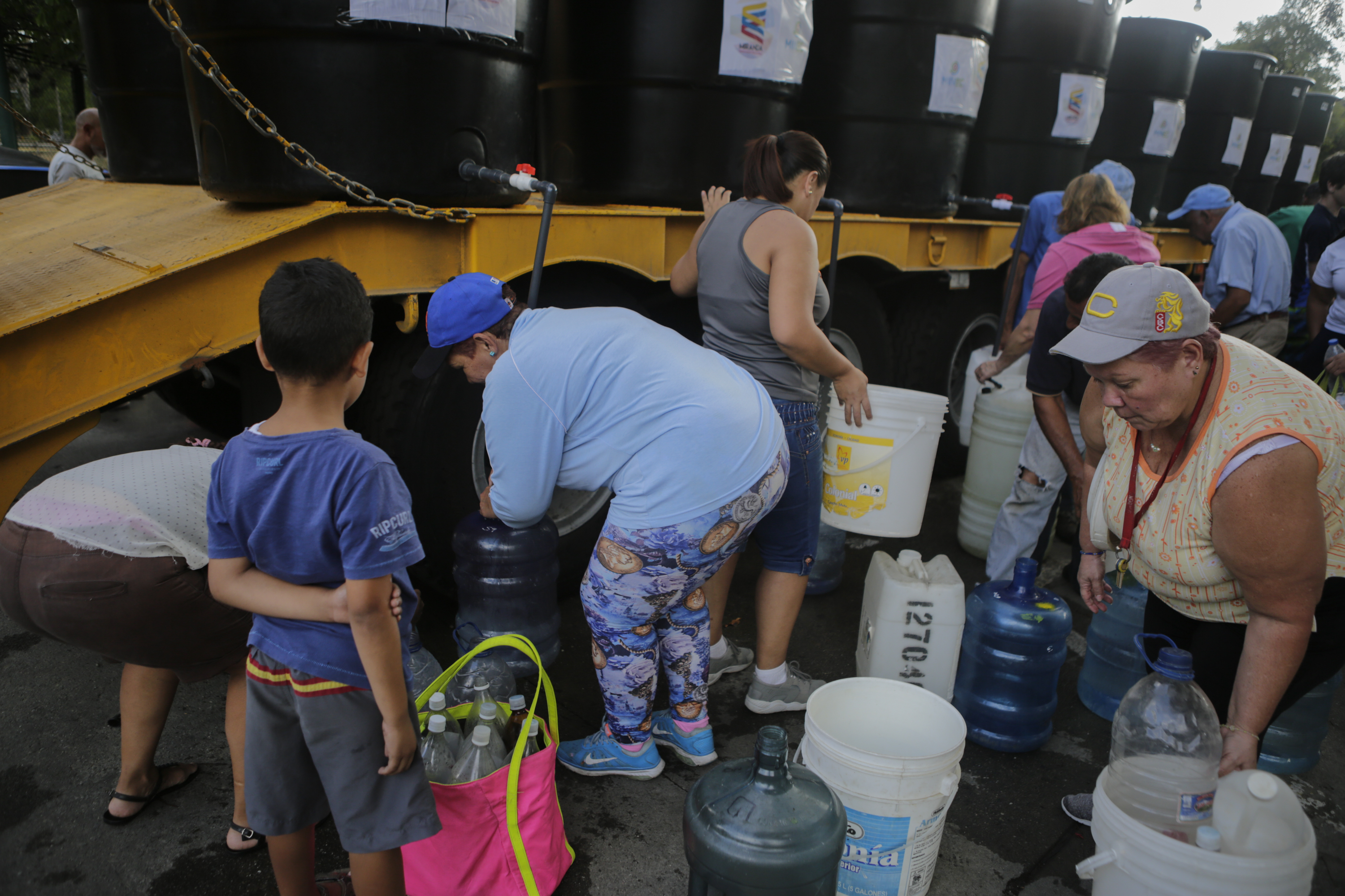 People fill containers with water from tanks in a service area organized to help the community by the Ministry of Popular Power for Ecosocialism and Waters in Parque del Este, on April 4, 2019 in Caracas, Venezuela. (Photo by Eva Marie Uzcategui / Getty Images)