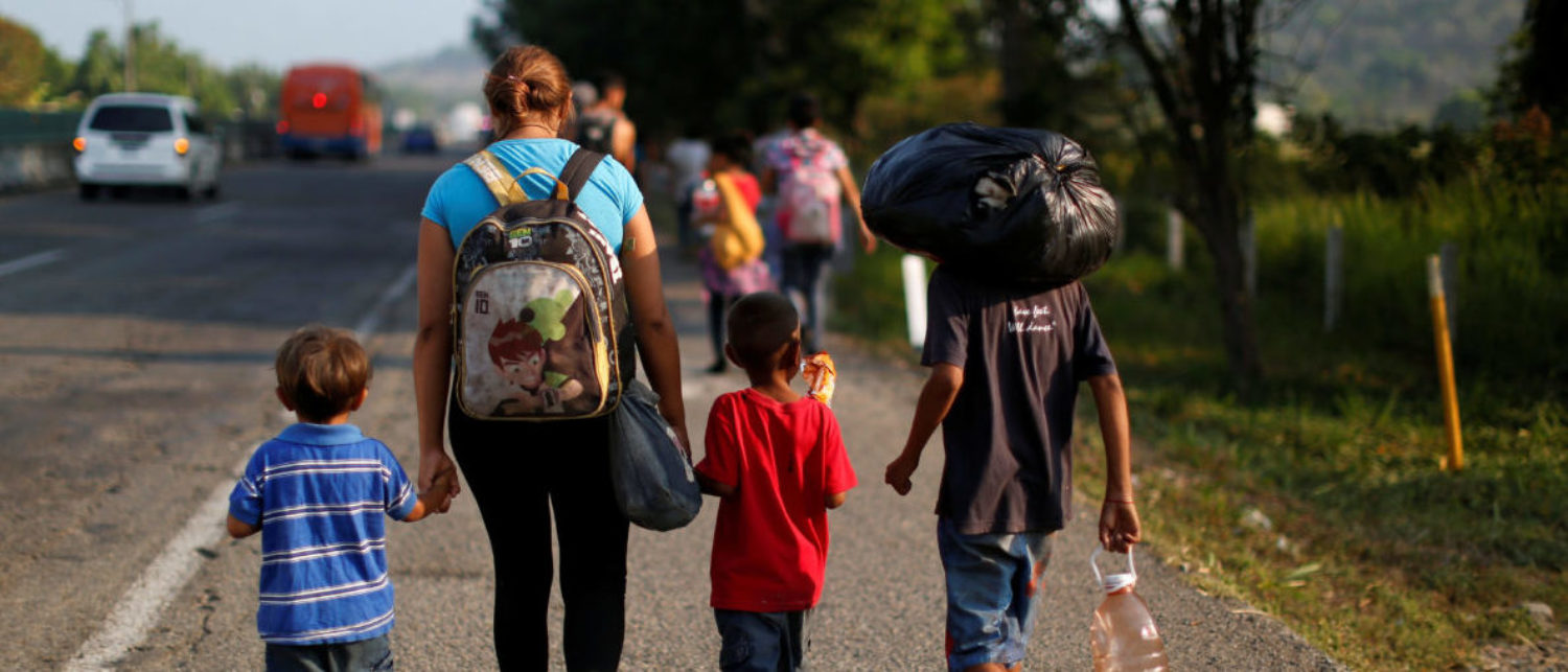 A migrant mother and her children walk along a road with other Central American migrants during their journey towards the United States, in Tuzantan