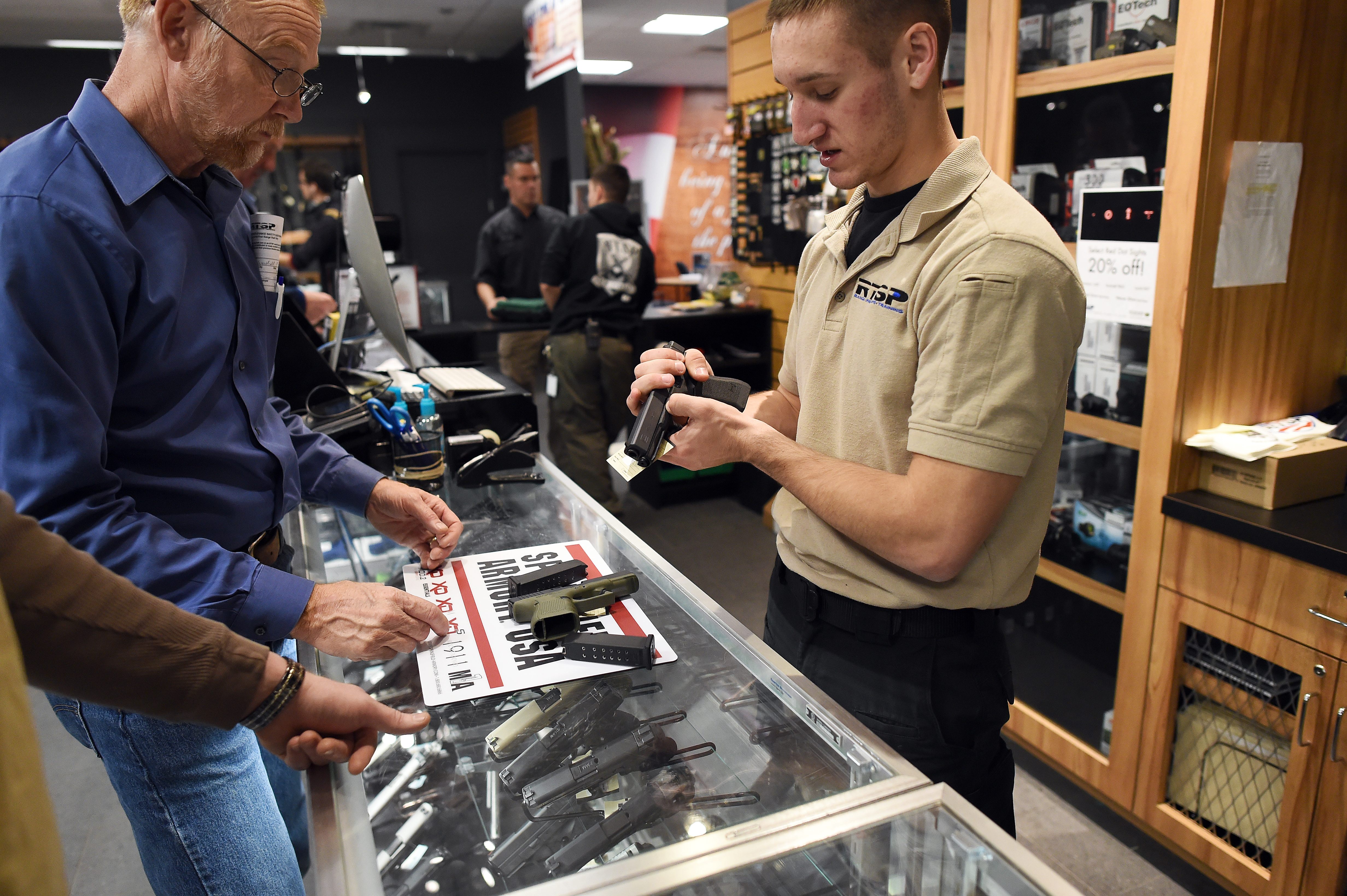 An employee shows handguns to customers at the RTSP shooting range in Randolph, New Jersey on December 9, 2015. (Photo by JEWEL SAMAD/AFP/Getty Images)