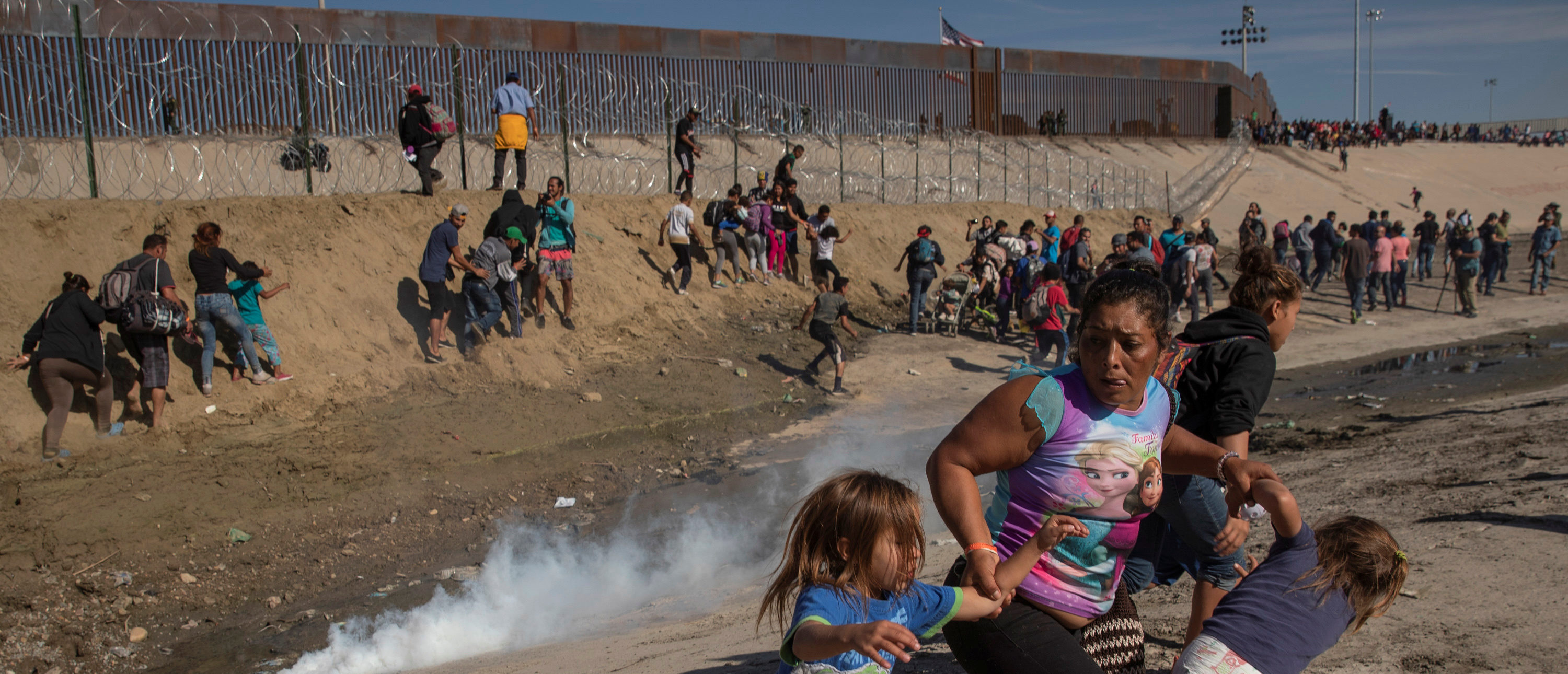 Maria Meza, a 40-year-old migrant woman from Honduras, part of a caravan of thousands from Central America trying to reach the United States, runs away from tear gas with her five-year-old twin daughters Saira Mejia Meza (L) and Cheili Mejia Meza (R) in front of the border wall between the U.S and Mexico, in Tijuana, Mexico November 25, 2018. REUTERS/Kim Kyung-hoon