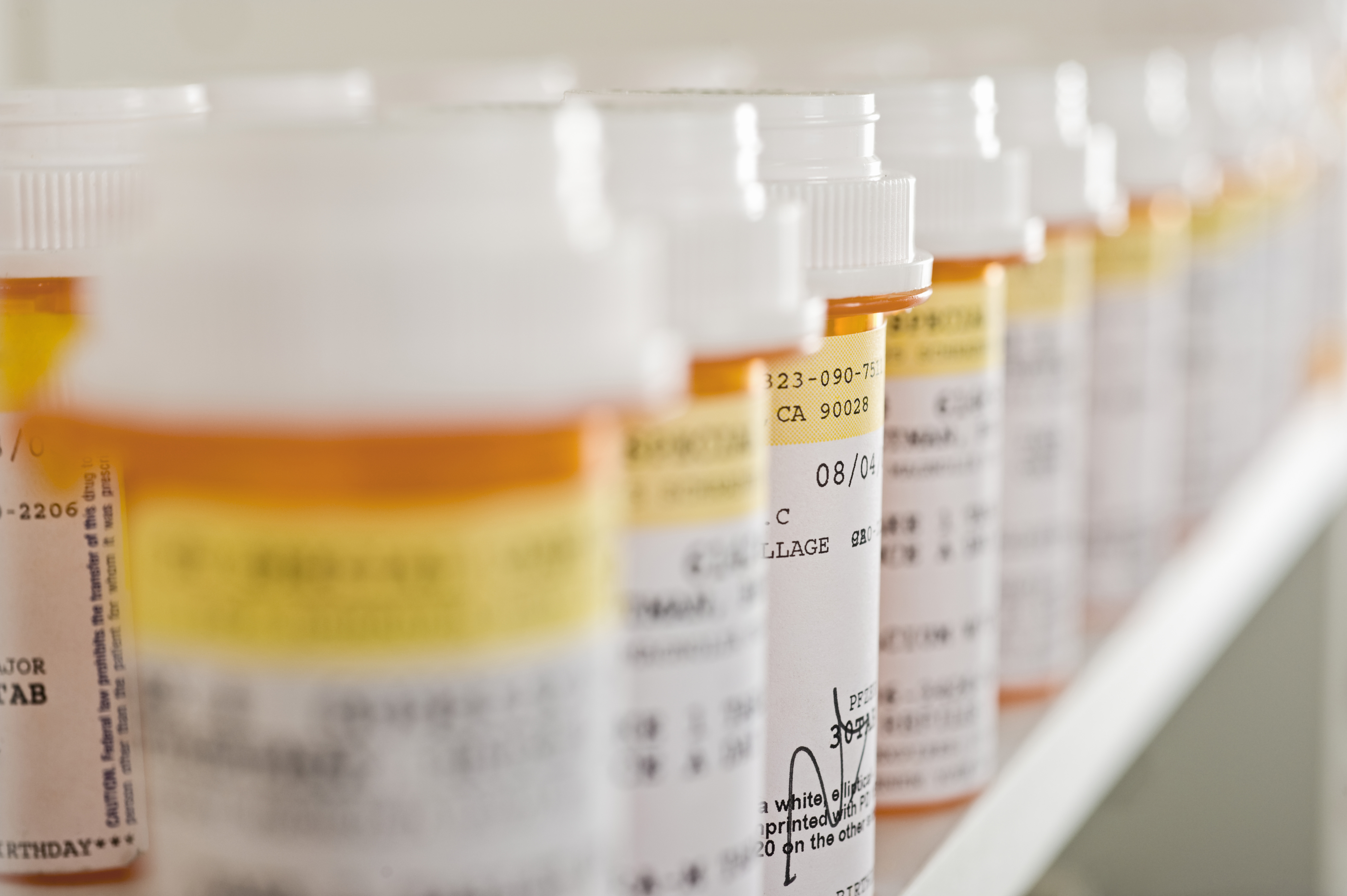 Pill bottles are arranged on a shelf. Shutterstock image via sirtravelsalot