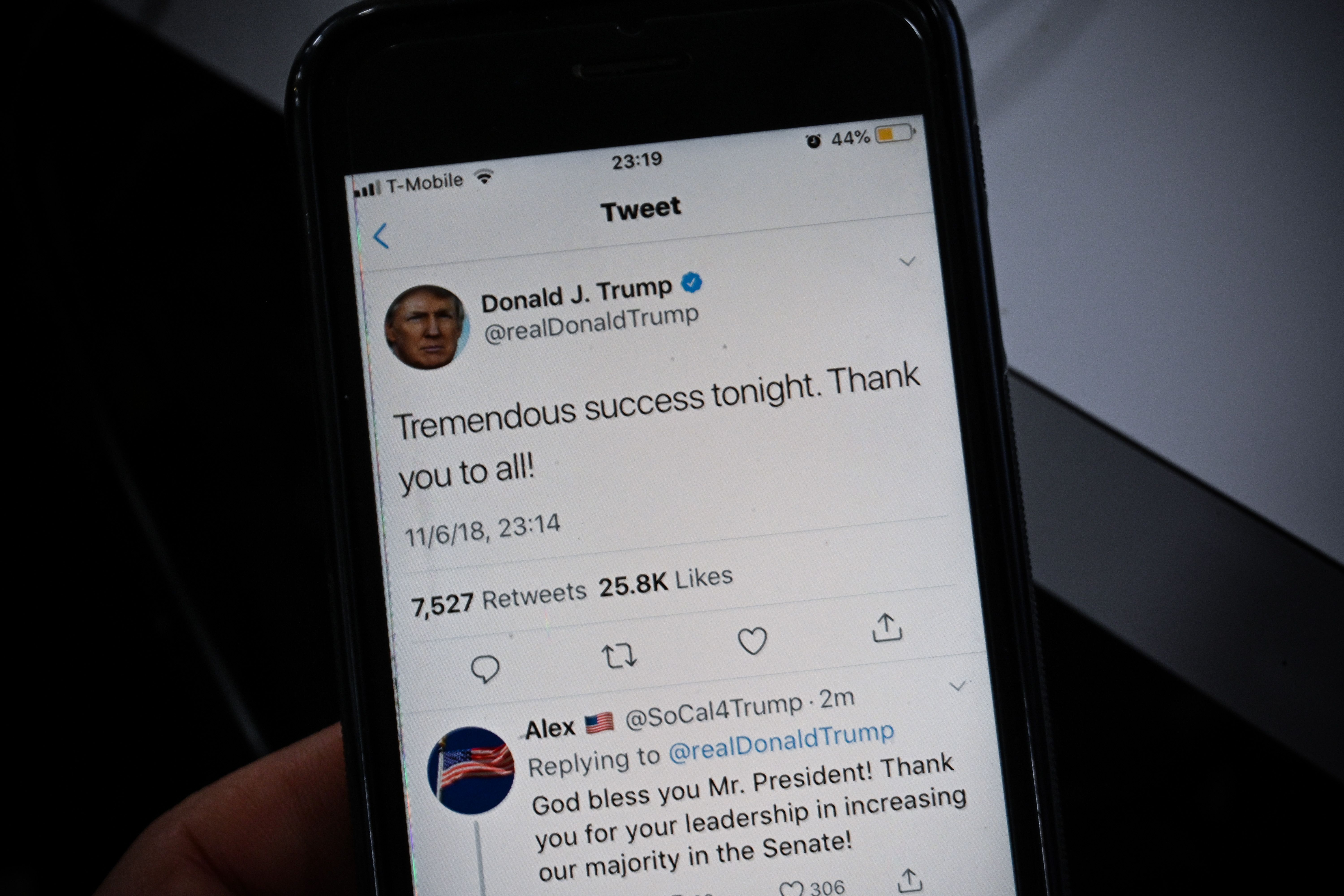 A smartphone shows a tweet by US President Donald Trump saying 