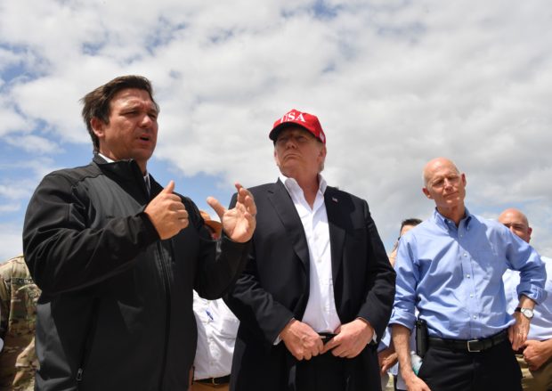 US President Donald Trump and Florida Republican US Senator Rick Scott (R) listen to Florida Governor Ron DeSantis (L) during a tour of the Edgar Hoover Dike on Lake Okeechobee in Florida, on March 29, 2019. (Photo by Nicholas Kamm / AFP) (Photo credit should read NICHOLAS KAMM/AFP/Getty Images)