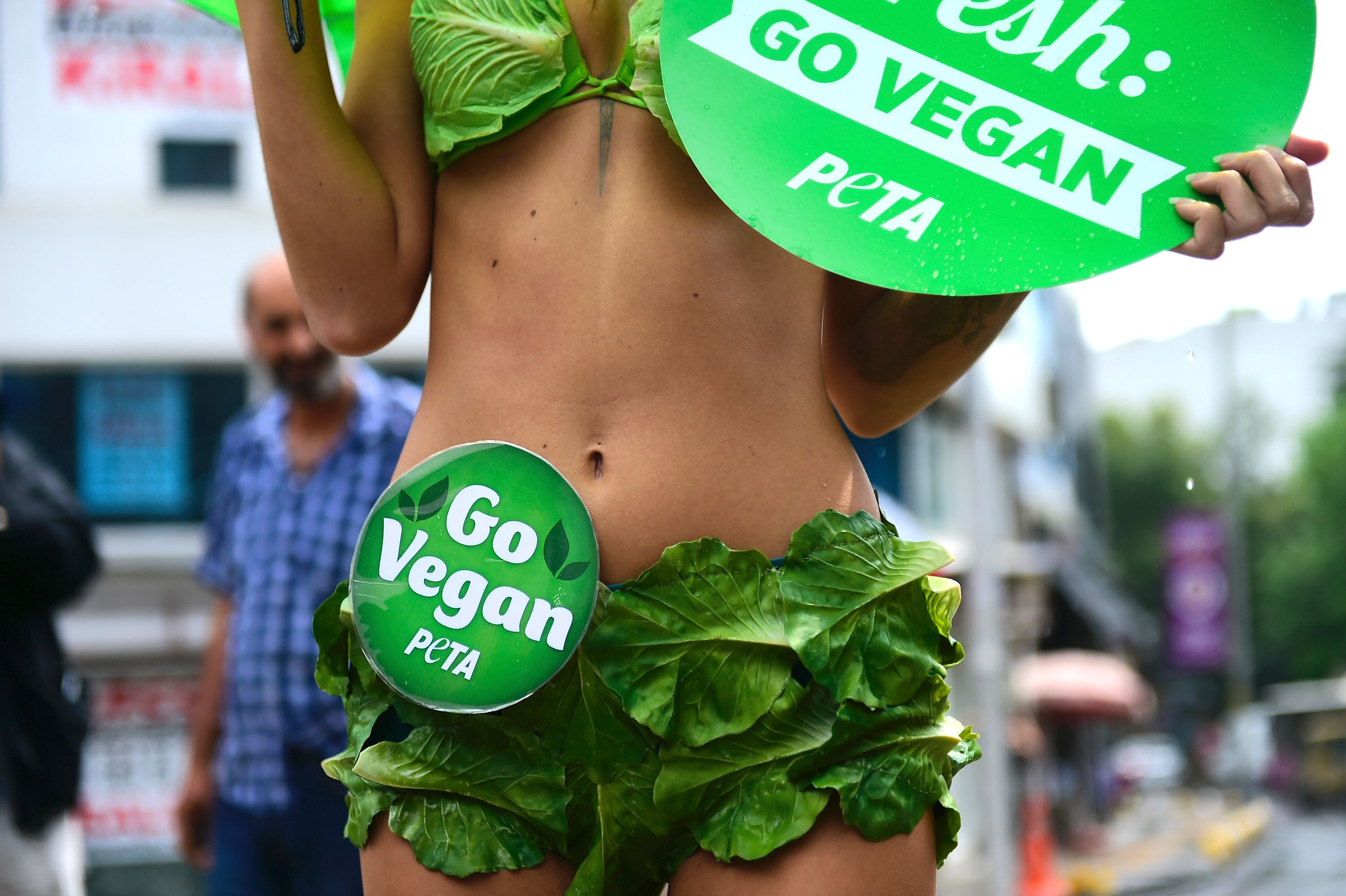 A woman wearing underwear made with salad and called "Lettuce Ladies", holds a placard reading ''start fresh, go vegan" during a demonstration of the US animal rights organisation People for the Ethical Treatment of Animals (PETA), next to a bull scultpure on August 17, 2017, at Kadikoy, in Istanbul. / AFP PHOTO / YASIN AKGUL (Photo credit should read YASIN AKGUL/AFP/Getty Images)