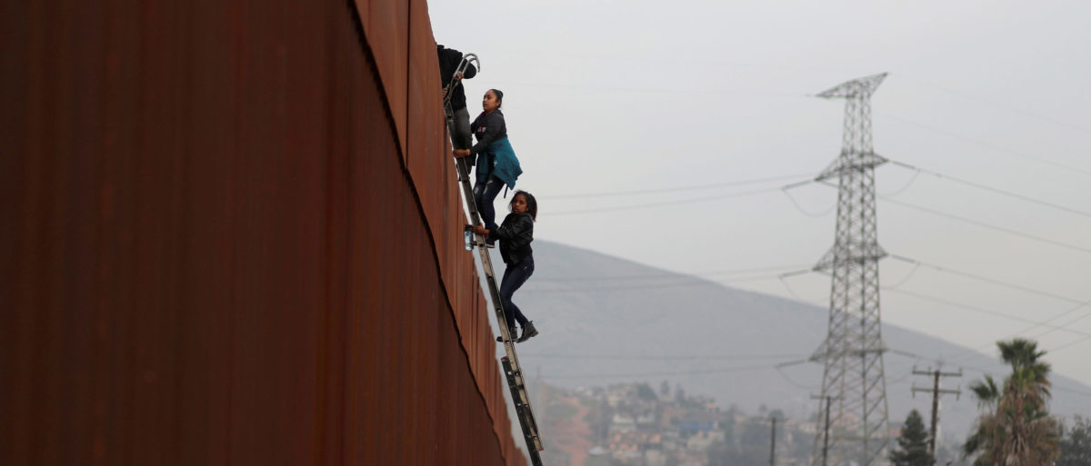 Migrants from Honduras, part of a caravan of thousands from Central America trying to reach the United States, climb a border fence to cross illegally from Mexico to the U.S., in Tijuana, Mexico, December 21, 2018. REUTERS/Mohammed Salem
