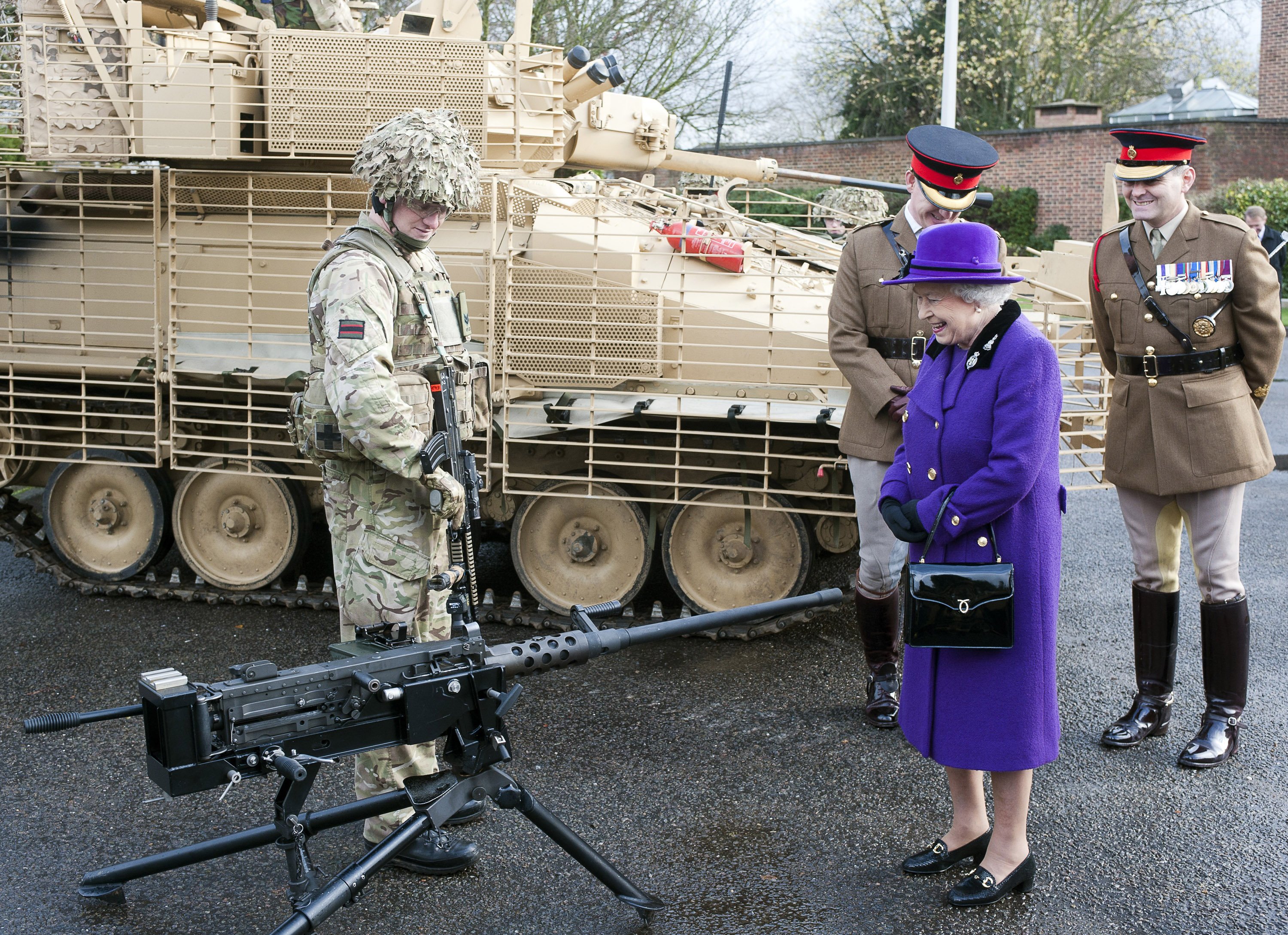 Queen Elizabeth II looks at a machine gun as she meets members of the Household Cavalry at Combermere Barracks on November 26, 2012 in Windsor, England. (Photo by David Parker - WPA Pool/Getty Images)
