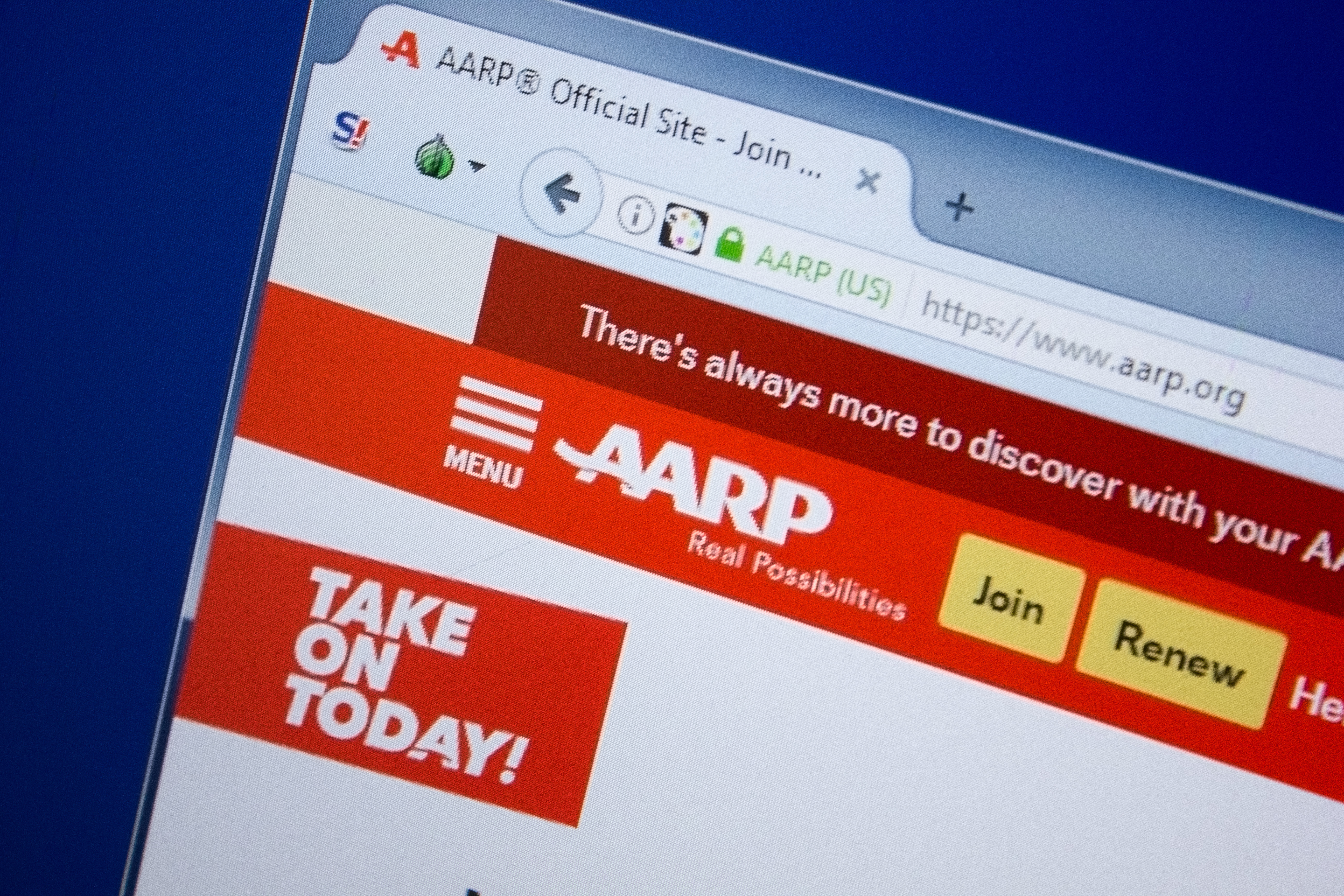 A screen shows the AARP website. Shutterstock image via Sharaf Maksumov