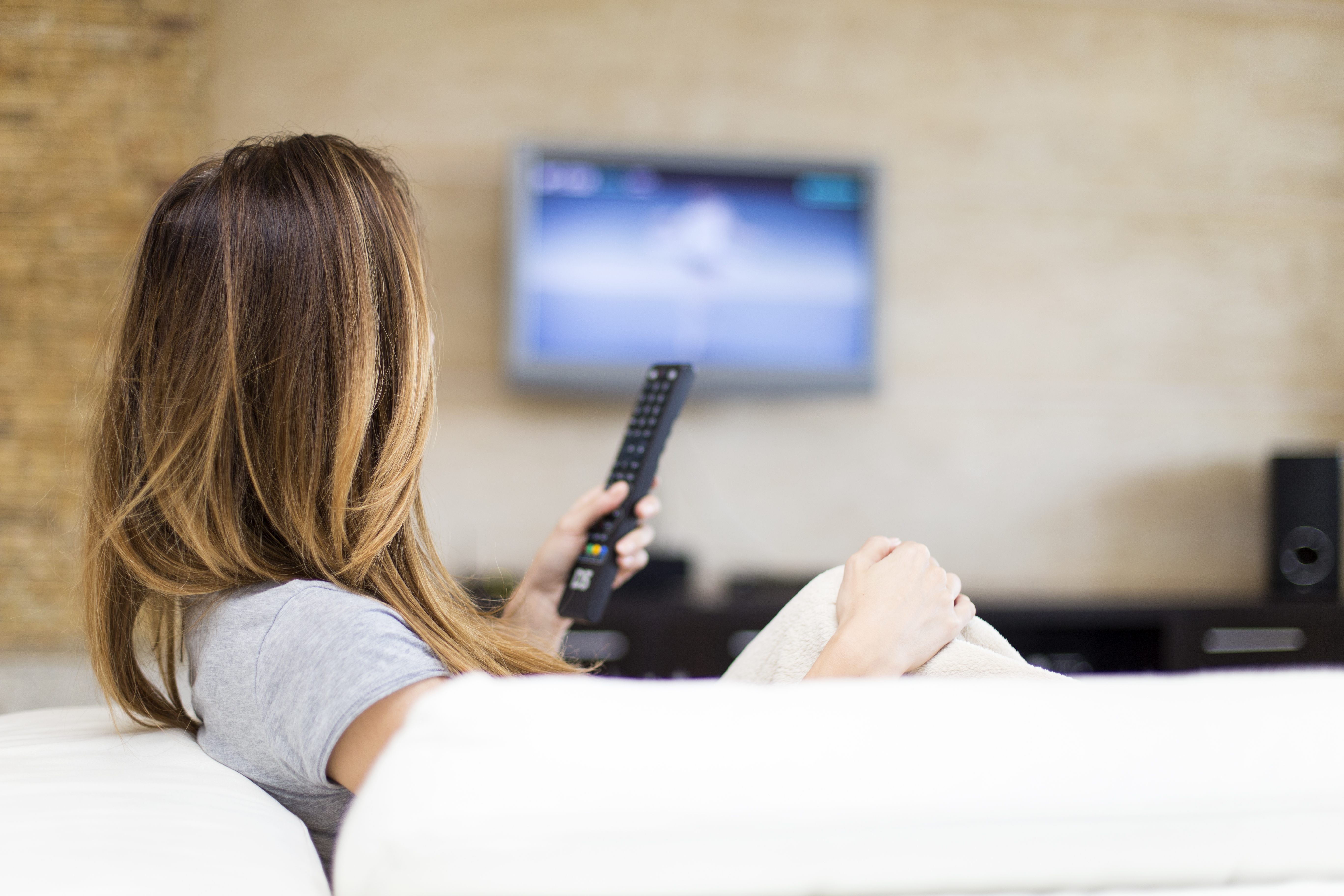 A woman watches television. Shutterstock image via Goran Bogicevic