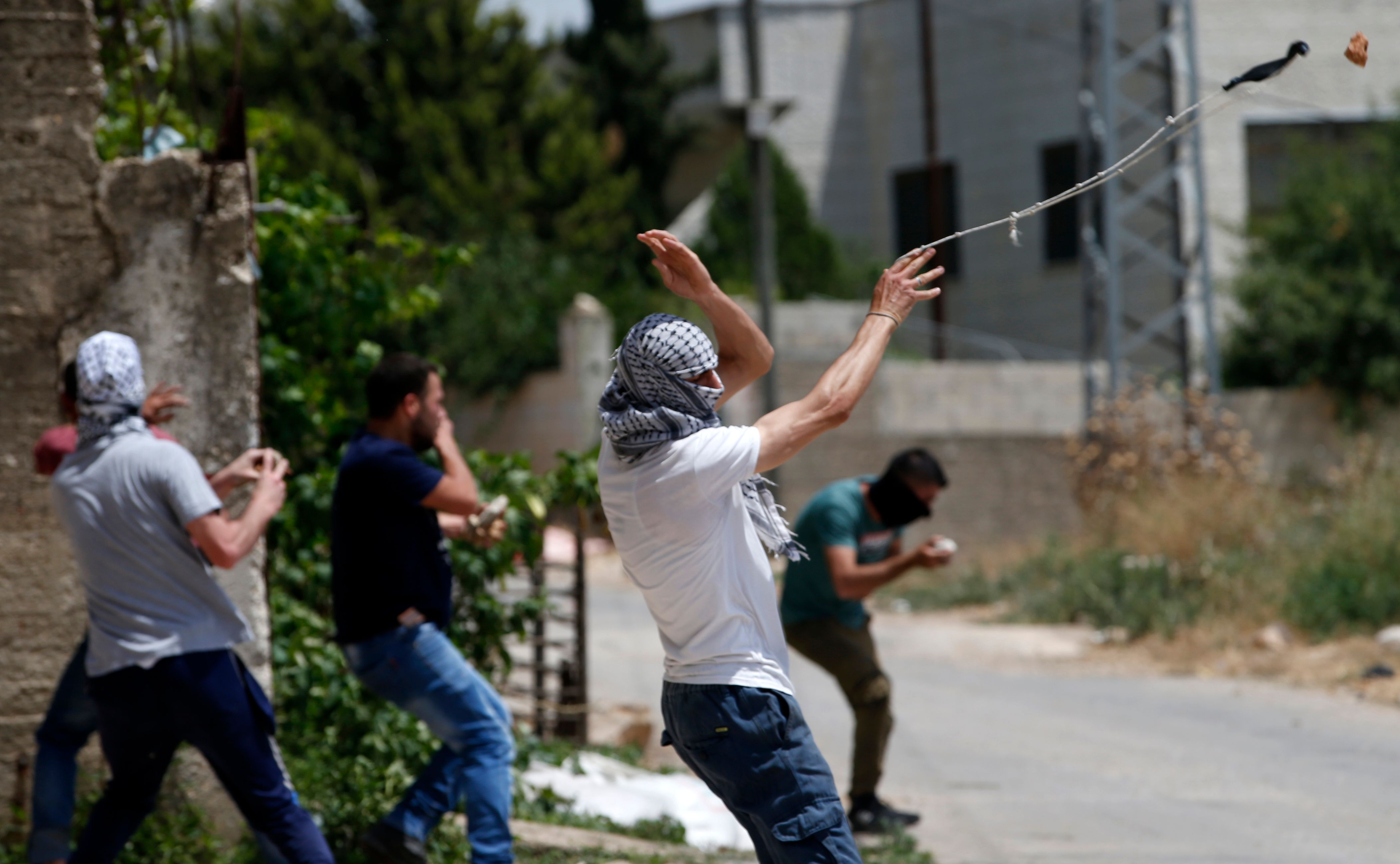 A Palestinian protester uses a slingshot to hurl objects during clashes with Israeli security forces following a weekly demonstration against the expropriation of Palestinian lands by Israel in the village of Kfar Qaddum, near Nablus in the West Bank, on May 31, 2019. (JAAFAR ASHTIYEH/AFP/Getty Images)