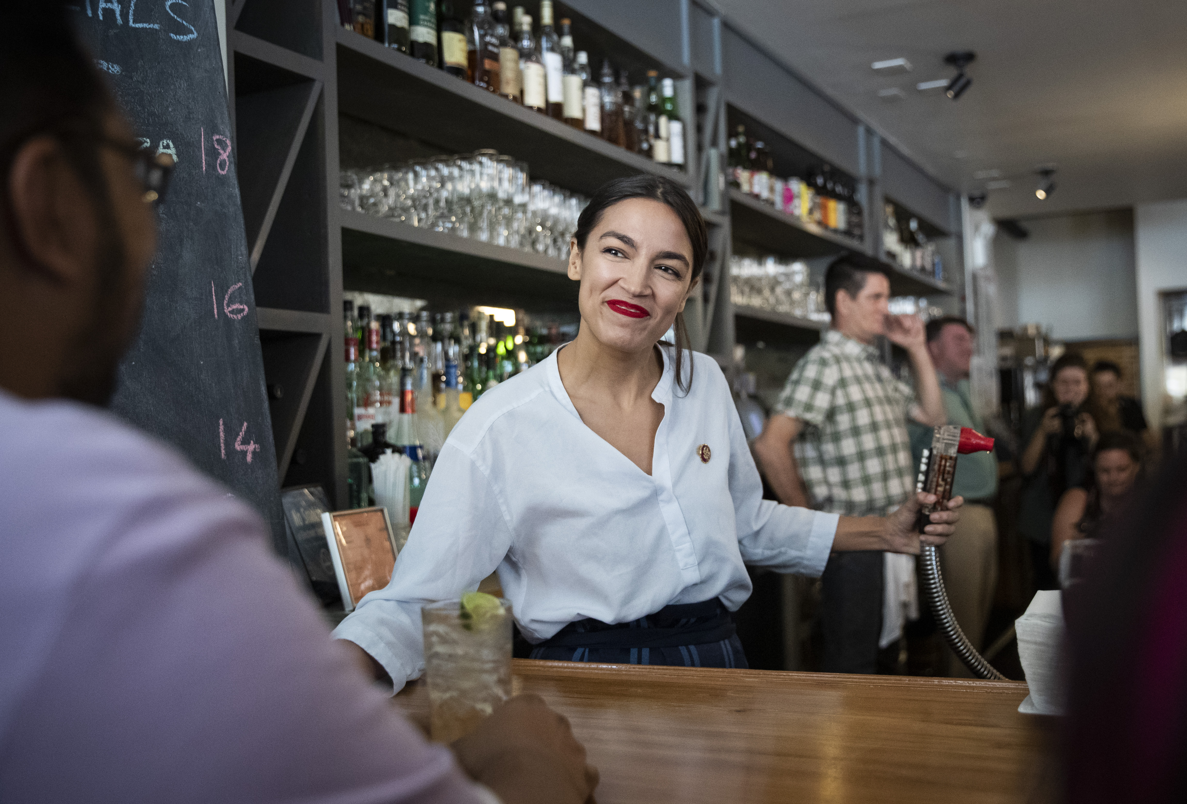 NEW YORK, NY - MAY 31: U.S. Rep. Alexandria Ocasio-Cortez (D-NY) works behind the bar at the Queensboro Restaurant, May 31, 2019 in the Queens borough of New York City. Ocasio-Cortez participated in an event to raise awareness for the One Fair Wage campaign, which calls to raise the minimum wage for tipped workers to a full minimum wage at the federal level. (Photo by Drew Angerer/Getty Images)
