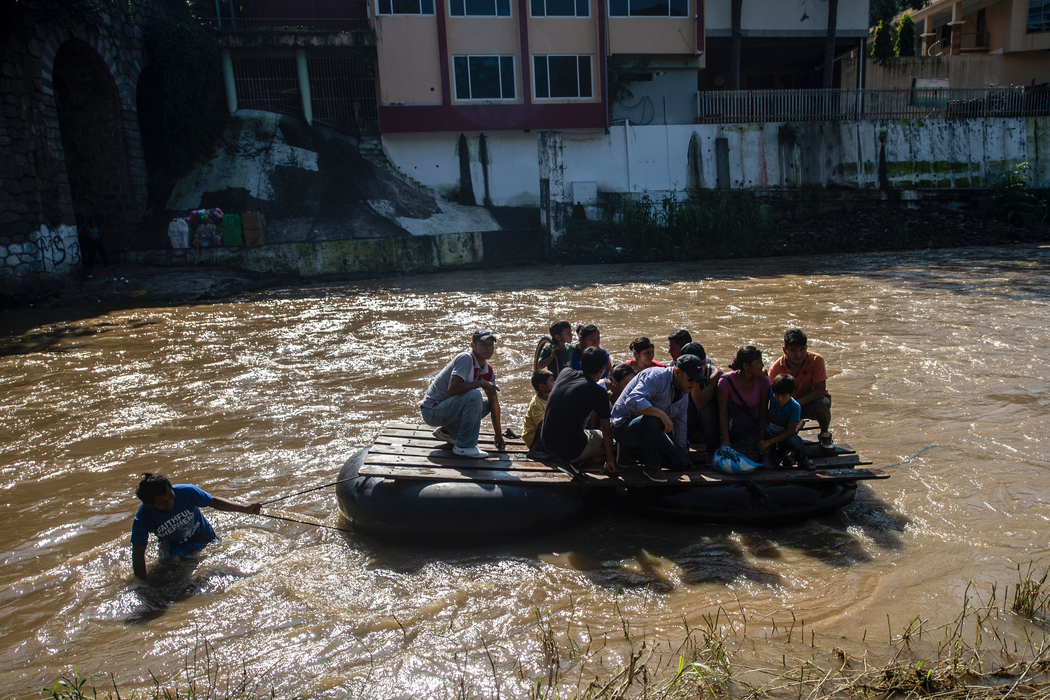 Migrants and residents use a makeshift raft to cross the Suchiate river from El Carmen in Guatemala to Talisman in Chiapas State, Mexico, on June 7, 2019. - The United States warned Friday that President Donald Trump's punitive tariffs on imports from Mexico were on course to take effect next week, despite headway in talks on stemming the surge in migration towards the US border. (Photo by PEDRO PARDO/AFP/Getty Images)