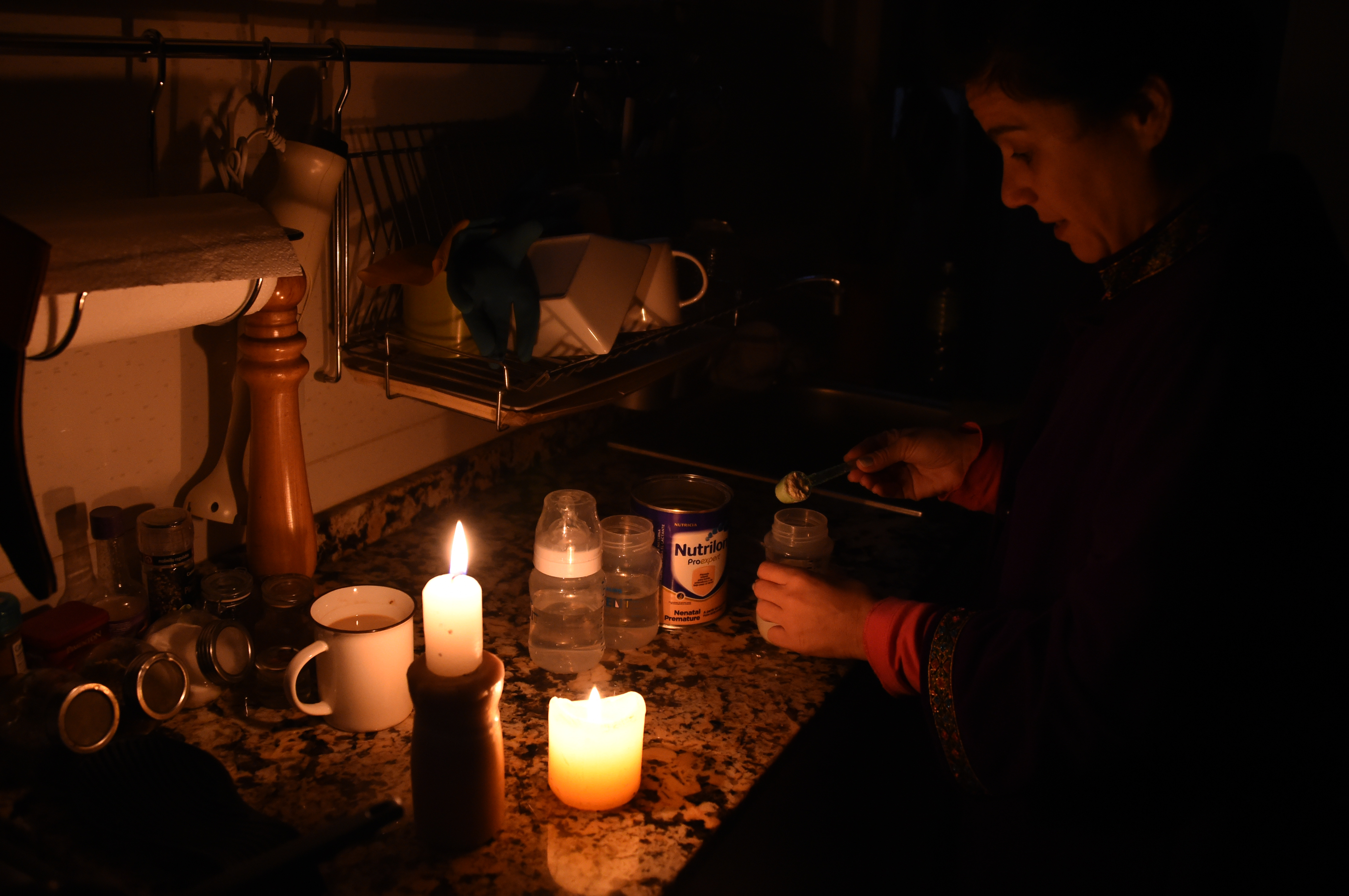 A woman prepares milk bottles using candles at her home in Montevideo on June 16, 2019 during a power cut. (MIGUEL ROJO/AFP/Getty Images)