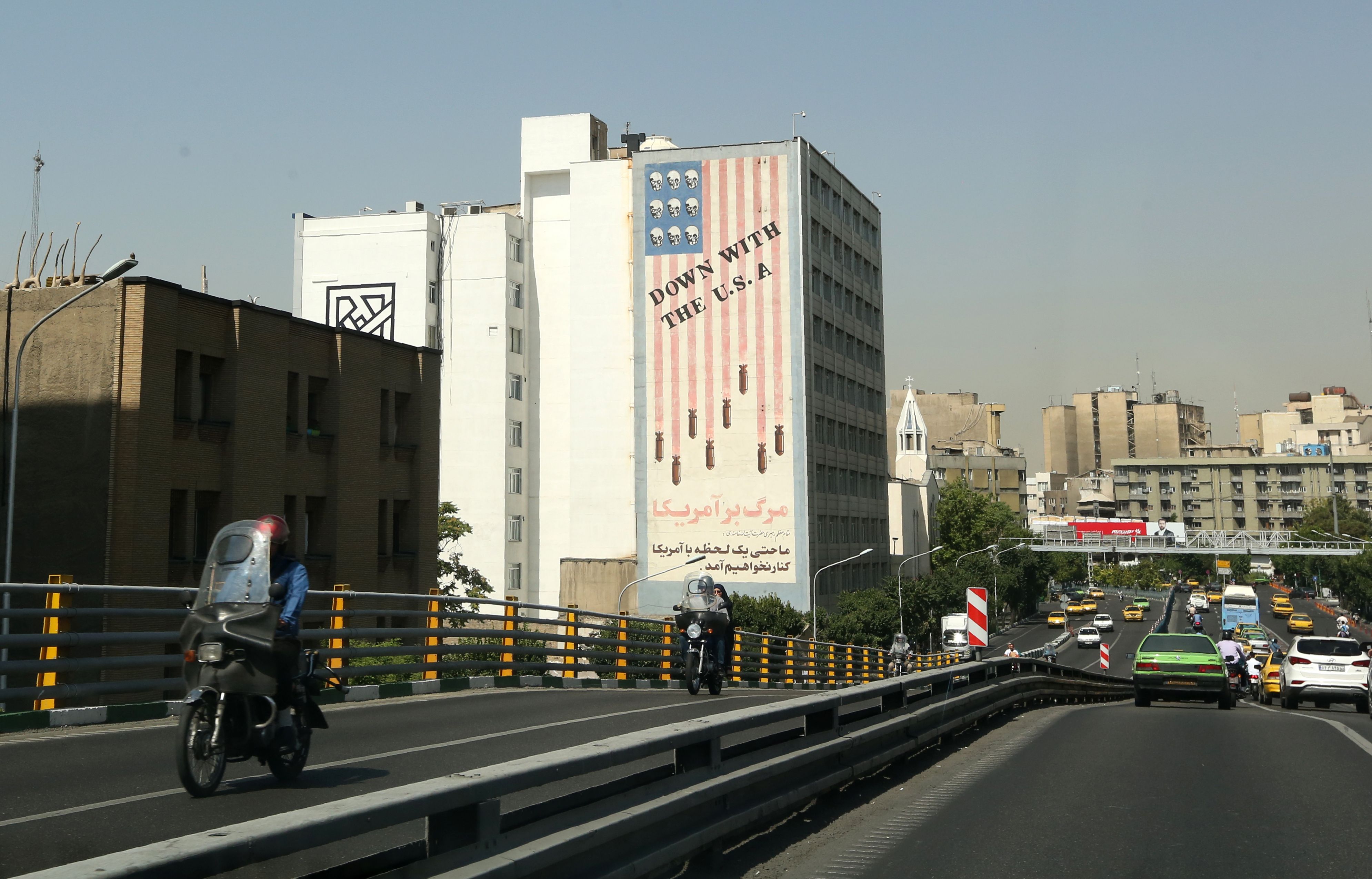 Cars drive past mural painting along the wall of a building in the Iranian capital Tehran on June 22, 2019. (Photo by ATTA KENARE / AFP) / The erroneous mention[s] appearing in the metadata of this photo by ATTA KENARE has been modified in AFP systems in the following manner: [wall of a building] instead of [wall of the former US embassy]. Please immediately remove the erroneous mention[s] from all your online services and delete it (them) from your servers. If you have been authorized by AFP to distribute it (them) to third parties, please ensure that the same actions are carried out by them. Failure to promptly comply with these instructions will entail liability on your part for any continued or post notification usage. Therefore we thank you very much for all your attention and prompt action. We are sorry for the inconvenience this notification may cause and remain at your disposal for any further information you may require.(ATTA KENARE/AFP/Getty Images)