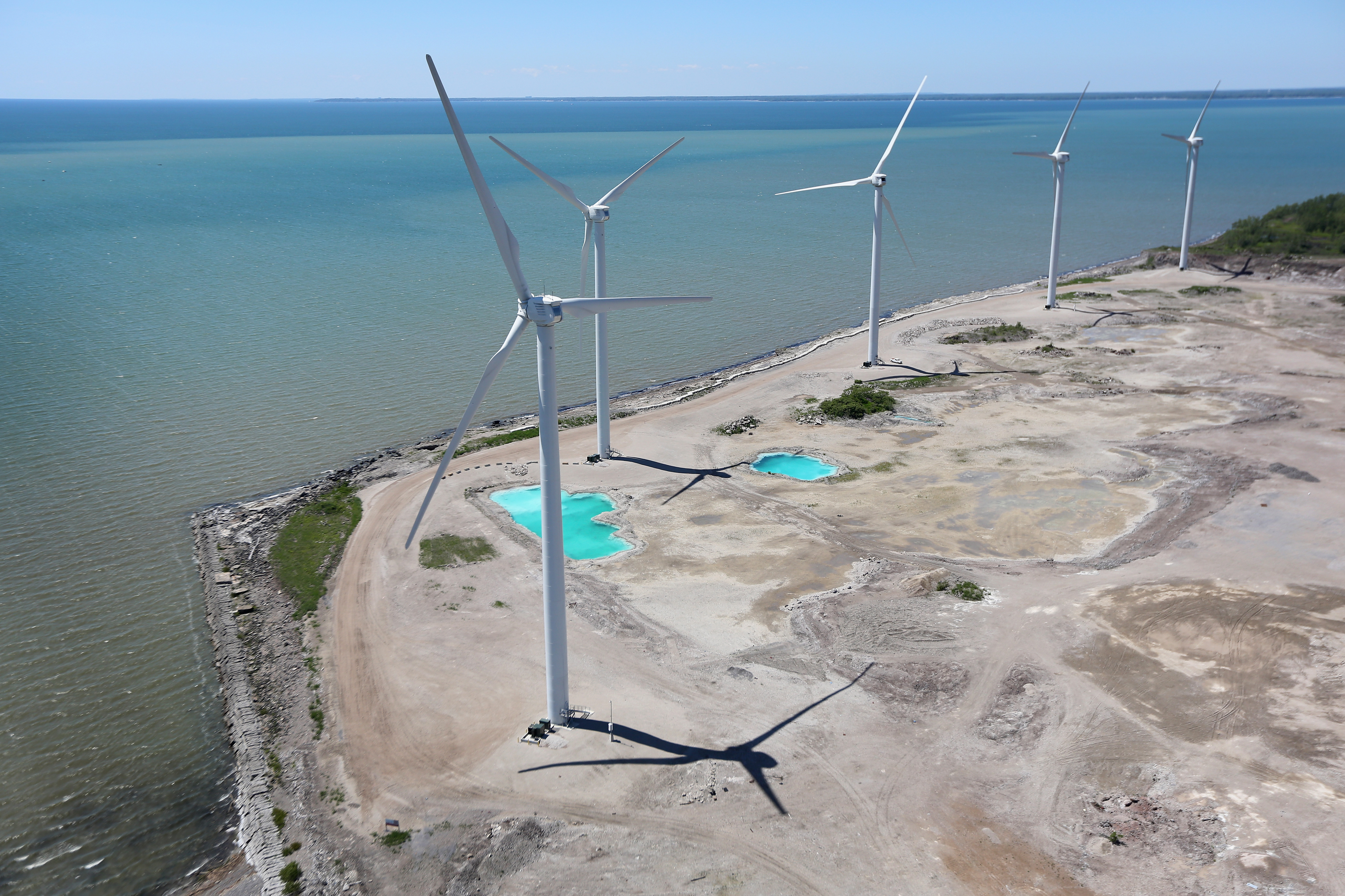 Wind Mills rise over Lake Erie on June 4, 2013 in Lackawanna, New York, near the U.S.-Canada border. The Steel Winds windmill farm, considered one of the largest urban renewable power developments in the world, is located on the grounds of the former Bethlehem Steel Plant. The aerial view was seen from a helicopter flown by the U.S. Office of Air and Marine, (OAM), which monitors and patrols the U.S.-Canada border. (Photo by John Moore/Getty Images)