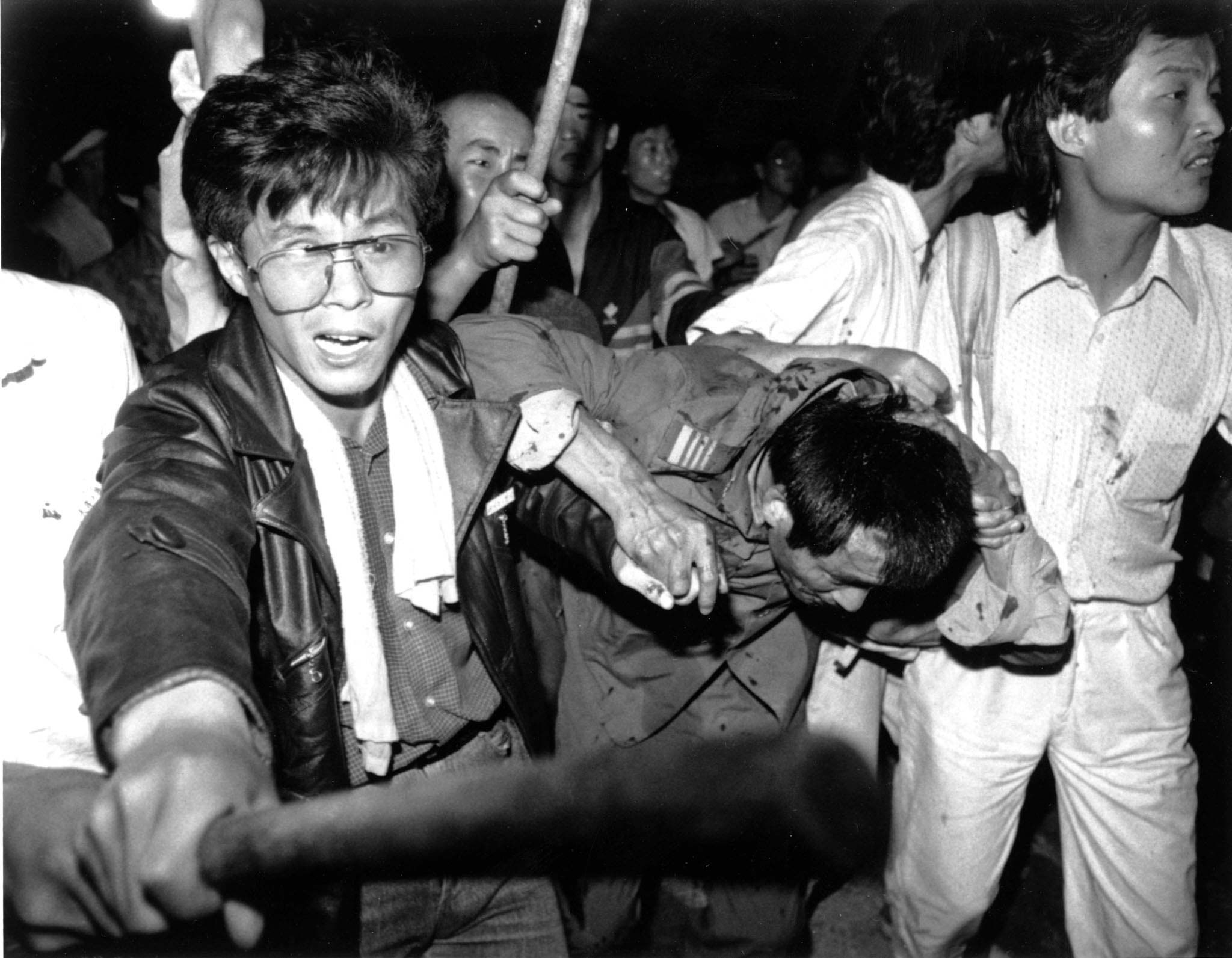 A captured tank driver is helped to safety by students as the crowd beats him June 4, 1989. This year marks the 10th anniversary of the bloody June 4 1989 army crackdown on the pro-democracy movement at Beijing's Tiananmen Square. Reuters/FILE