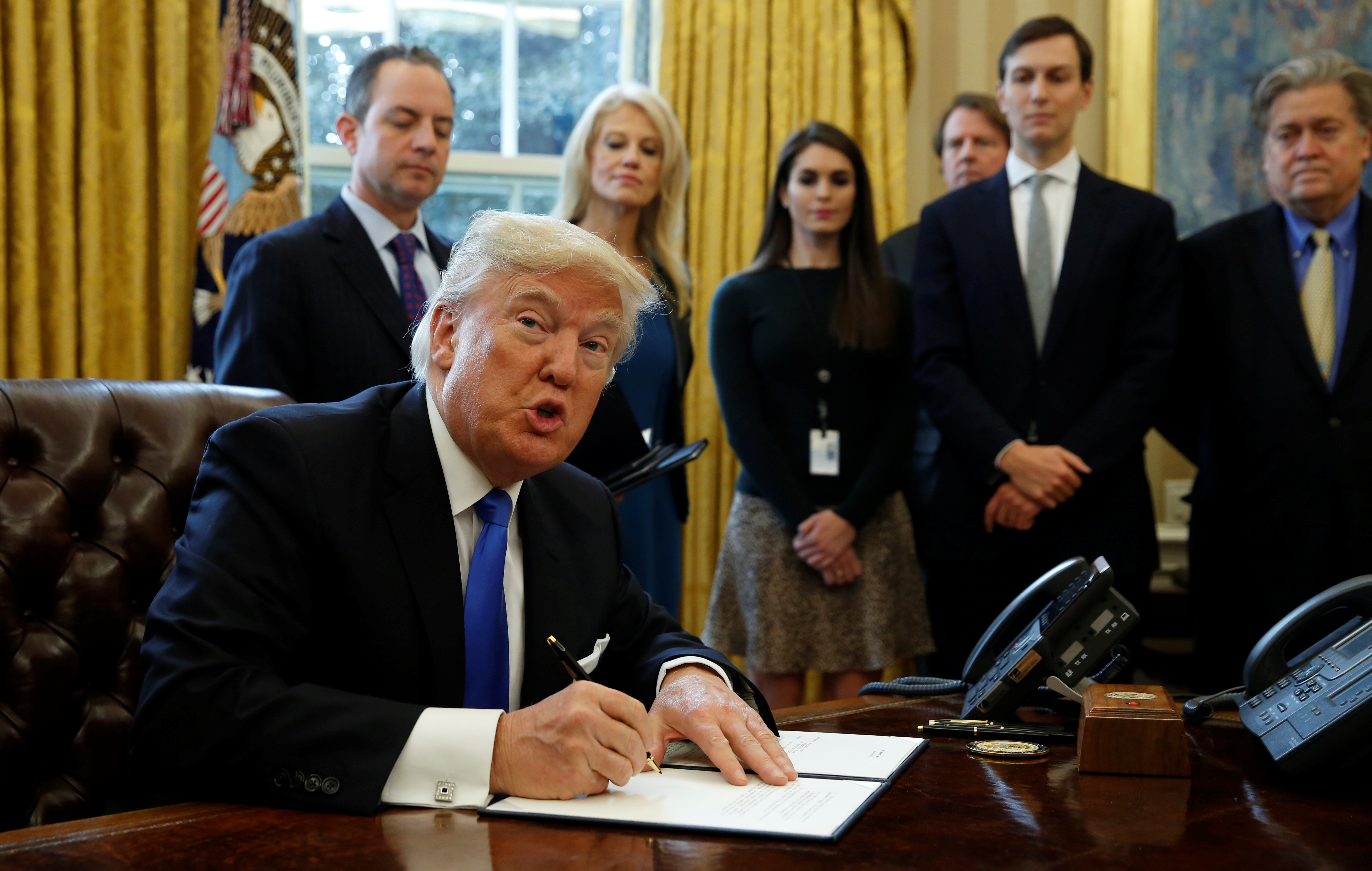 U.S. President Donald Trump looks up while signing an executive order to advance construction of the Keystone XL pipeline at the White House in Washington January 24, 2017. REUTERS/Kevin Lamarque 