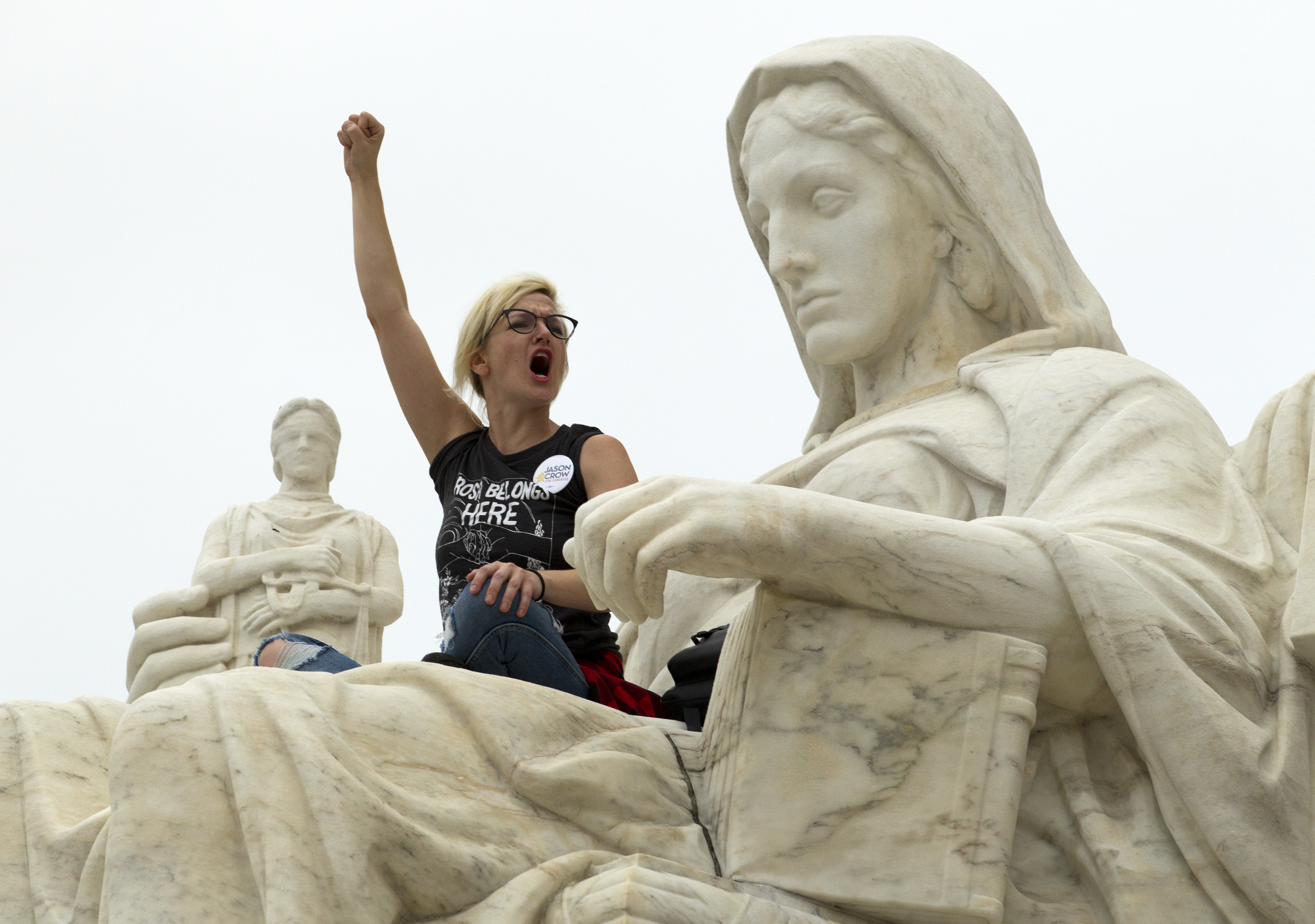 Demonstrator Jessica Campbell-Swanson of Denver stands on the "Contemplation of Justice" statue as protestors take the steps of the Supreme Court to picket against the confirmation of Justice Brett Kavanaugh on October 6, 2018. (Jose Luis Magana/AFP/Getty Images)