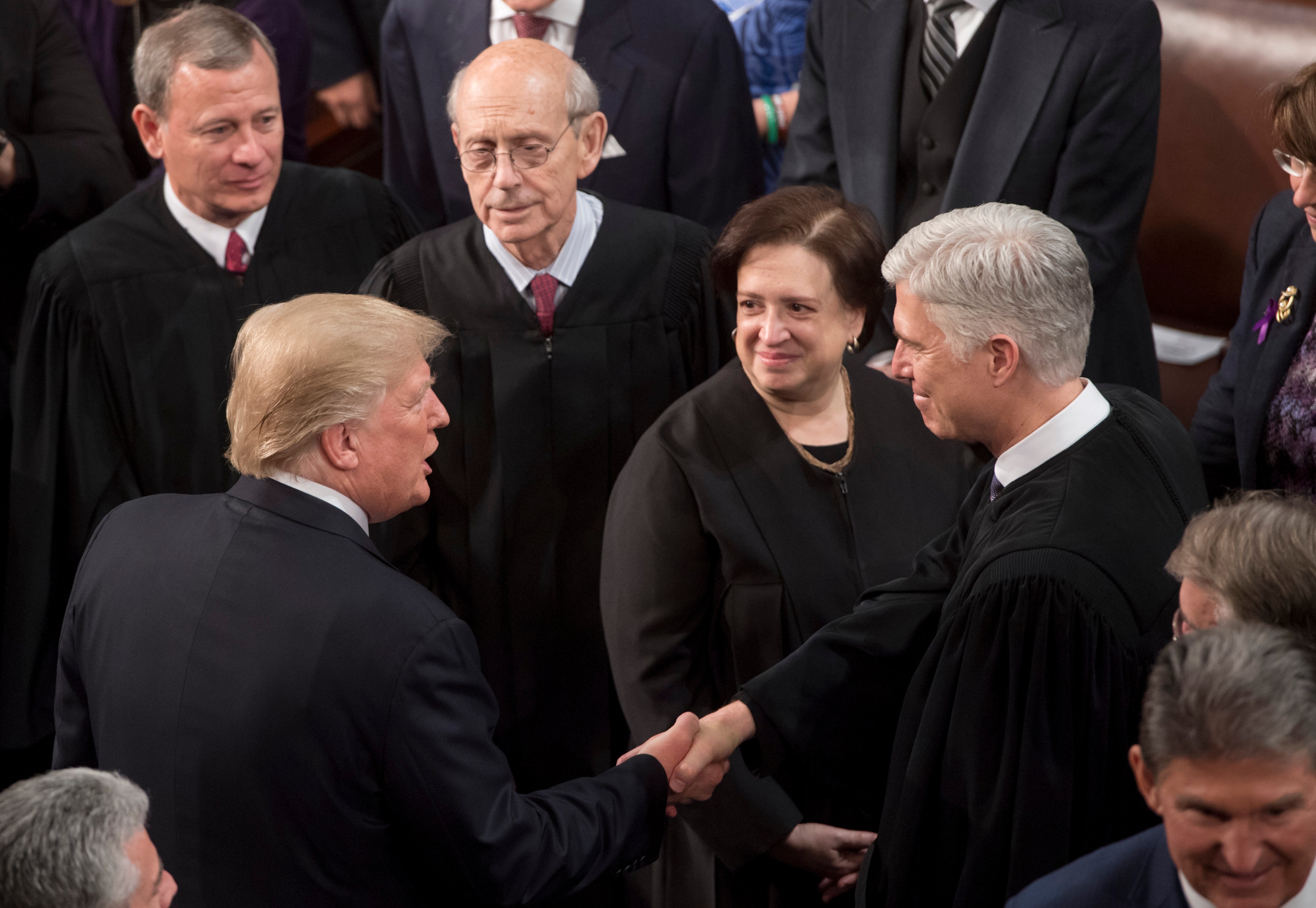 President Donald Trump shakes hands with Justice Neil Gorsuch as other members of the Supreme Court look on during the State of the Union address on January 30, 2018. (Saul Loeb/AFP/Getty Images)