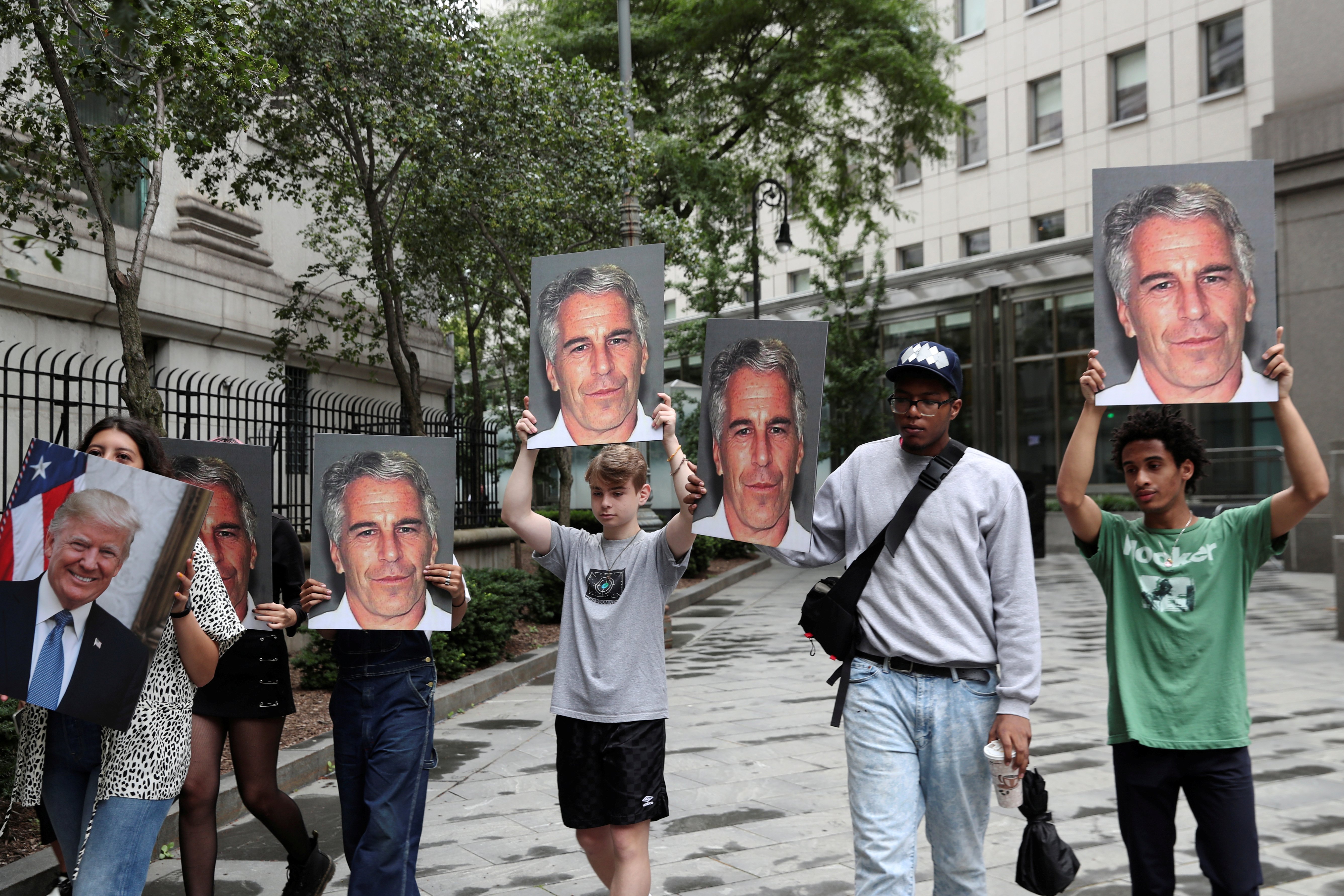 Demonstrators hold signs aloft protesting Jeffrey Epstein, as he awaits arraignment in the Southern District of New York on charges of sex trafficking of minors and conspiracy to commit sex trafficking of minors, in New York, U.S., July 8, 2019. REUTERS/Shannon Stapleton 